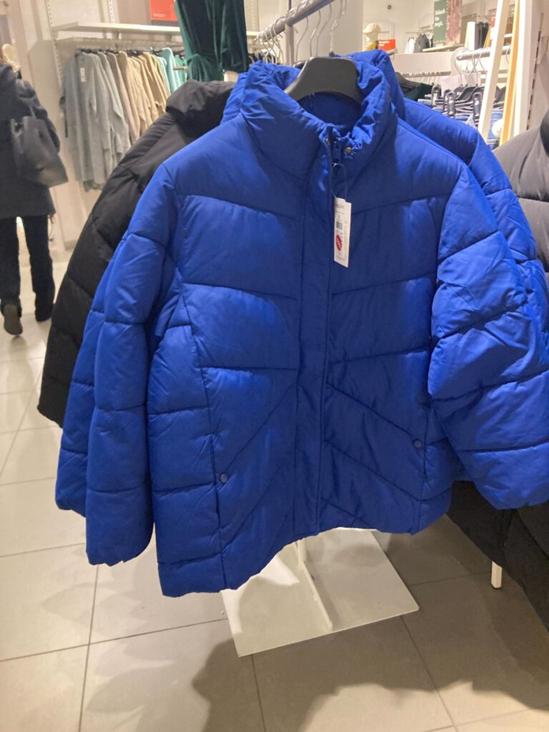 A blue winter jacket on display in a clothing store.