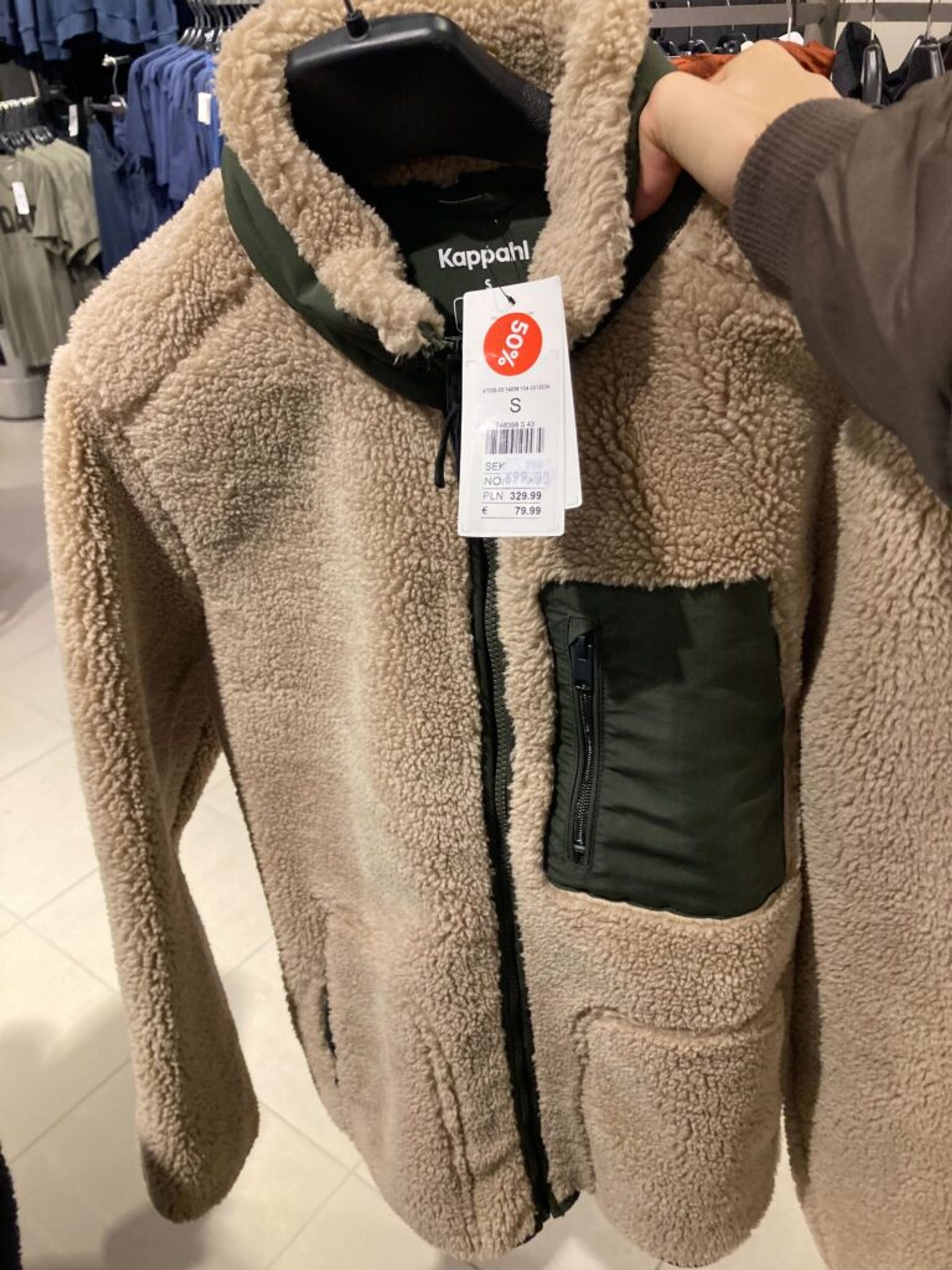 A fluffy jacket with a discount tag on display in a clothing store.