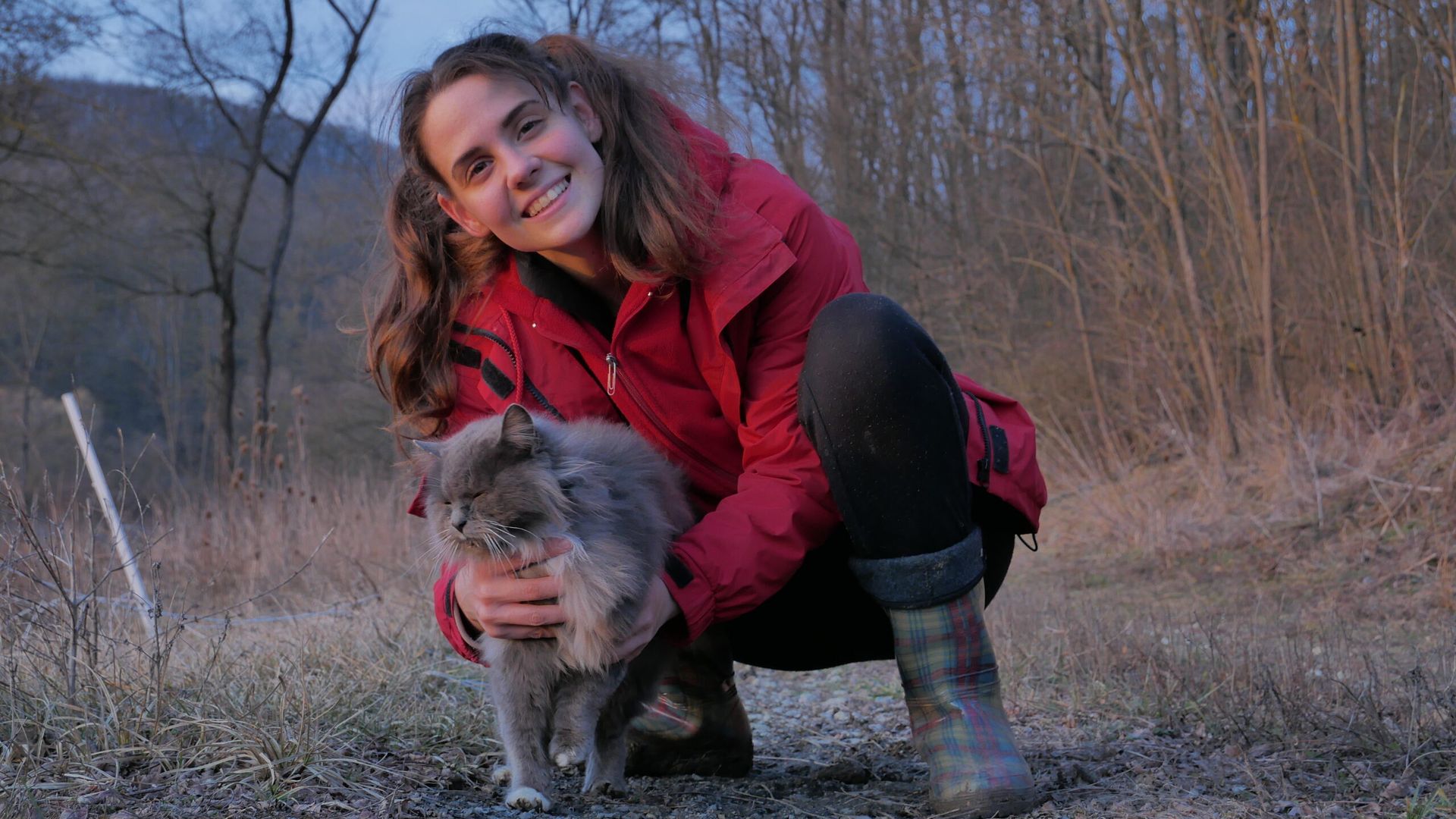 A woman poses with a grey-haired cat.