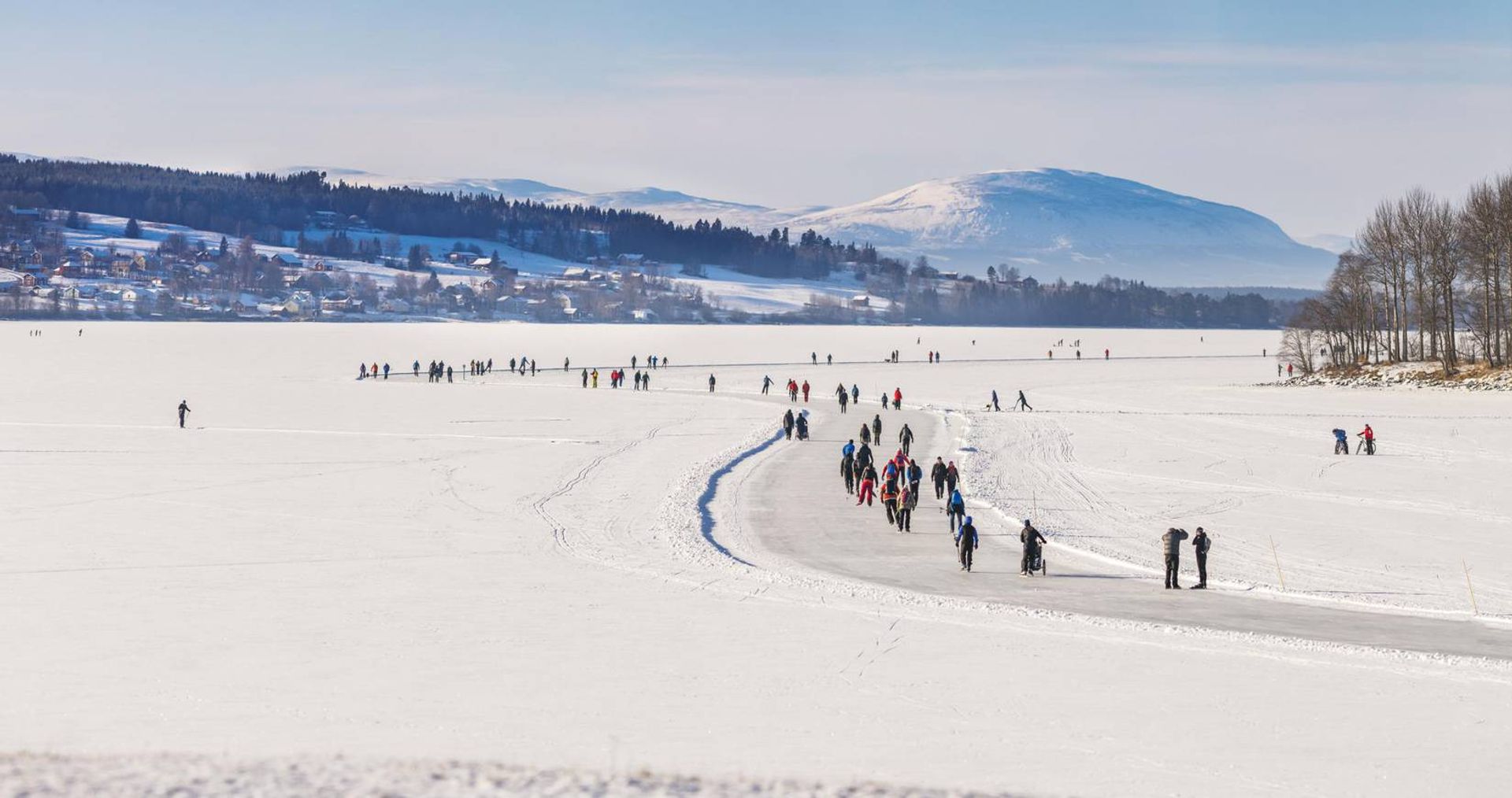 Skaters glide across an open field with mountains in the background.