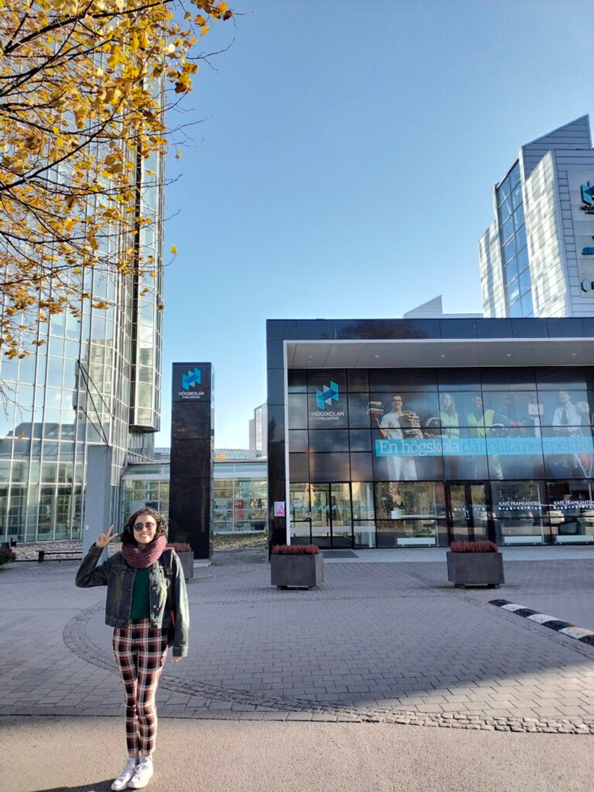 A woman stands in front of the entrance to a campus building at Halmstad University.