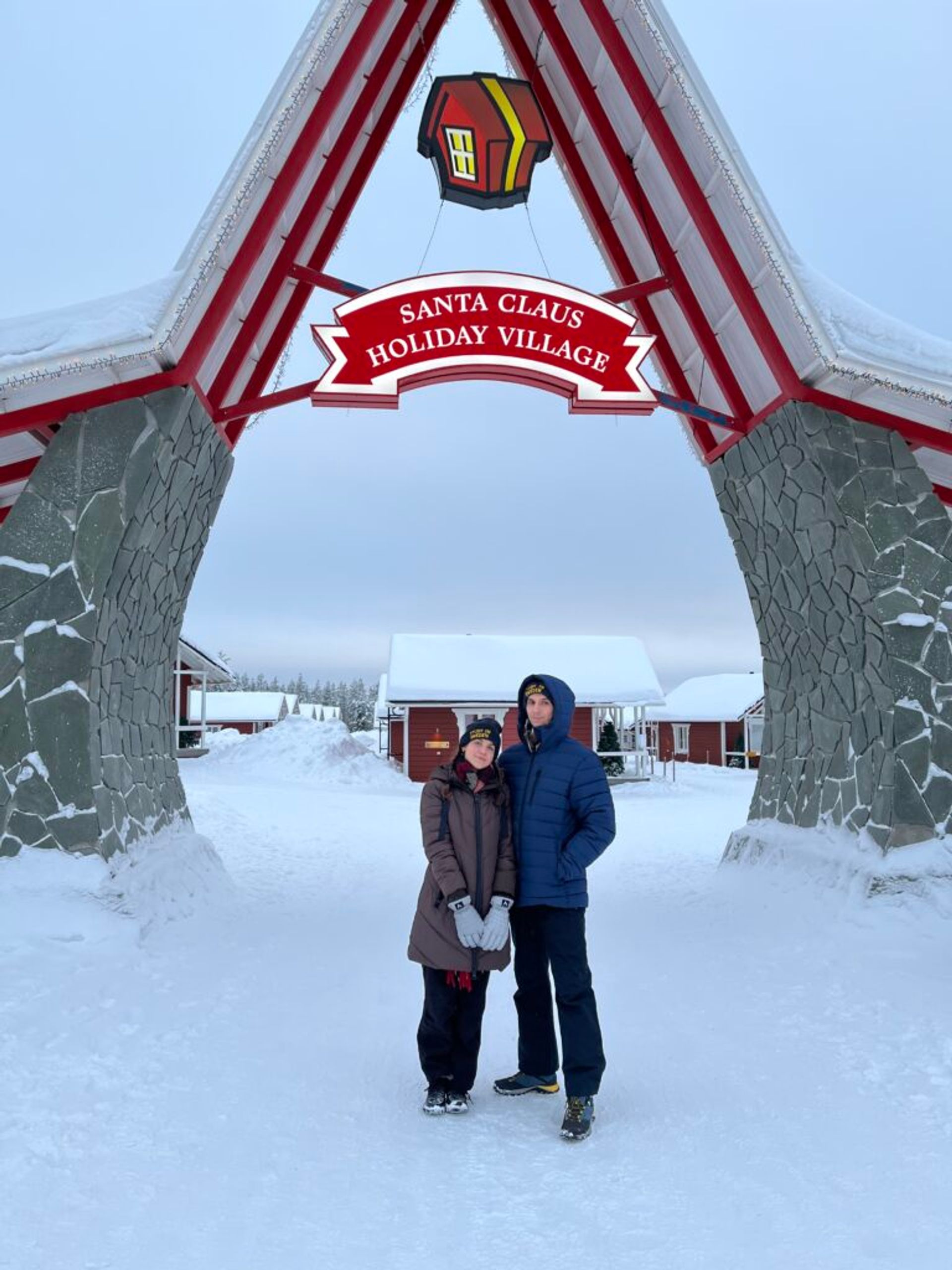 Two people stand in front of the entrance to Santa's Holiday Village.