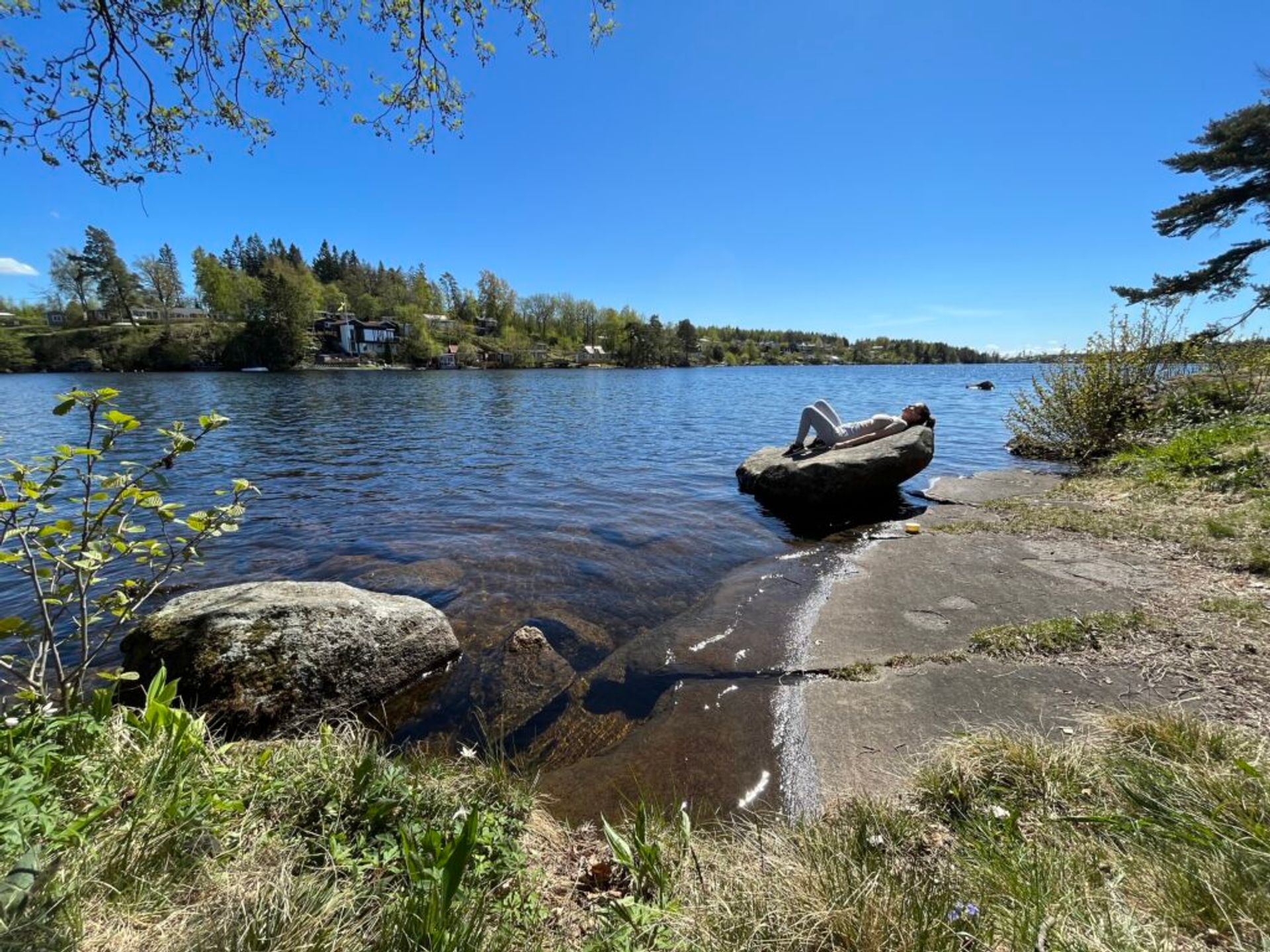 A girl lying on a rock by a lake. 