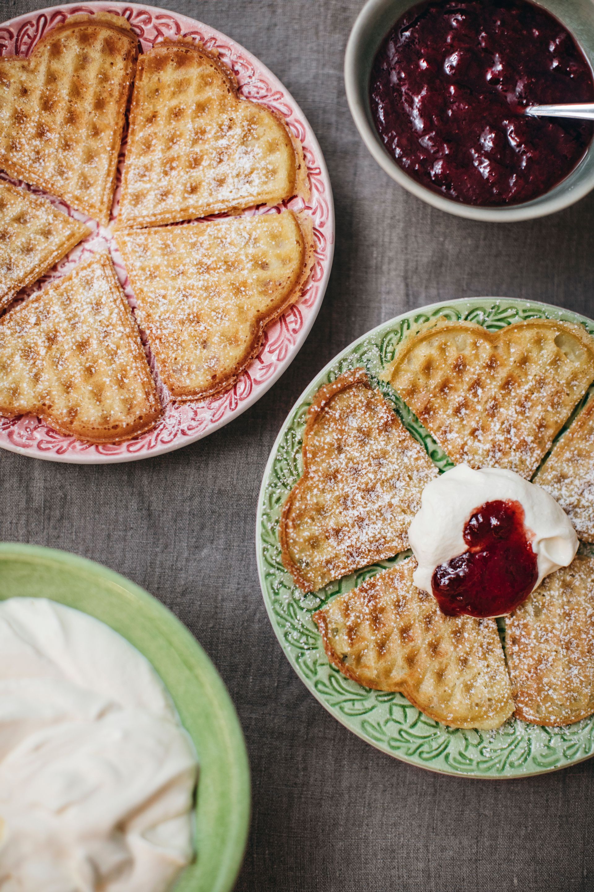 A table set with waffles, whipped cream and jam.