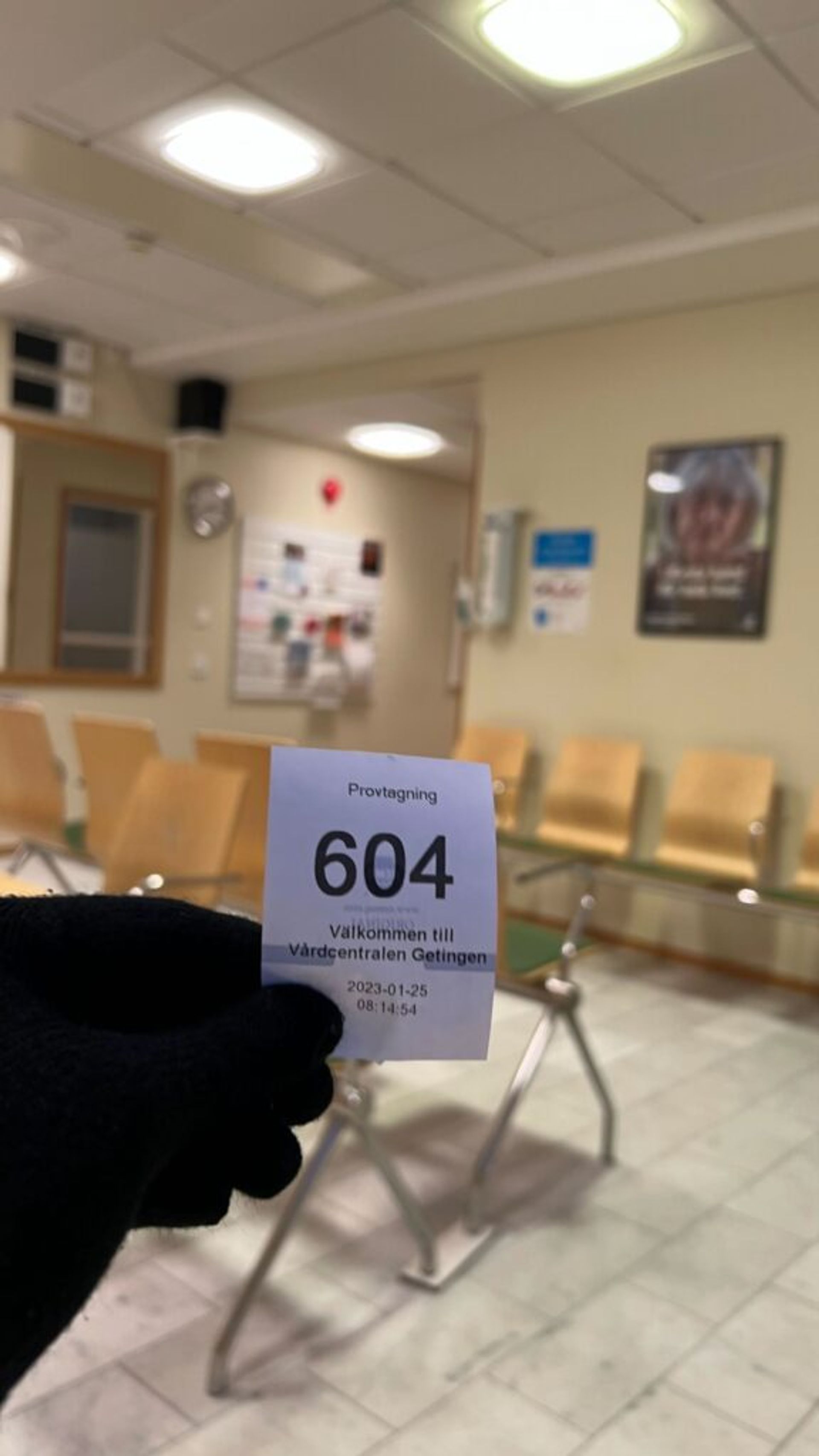 A close-up of a hand holding a hospital queue ticket.