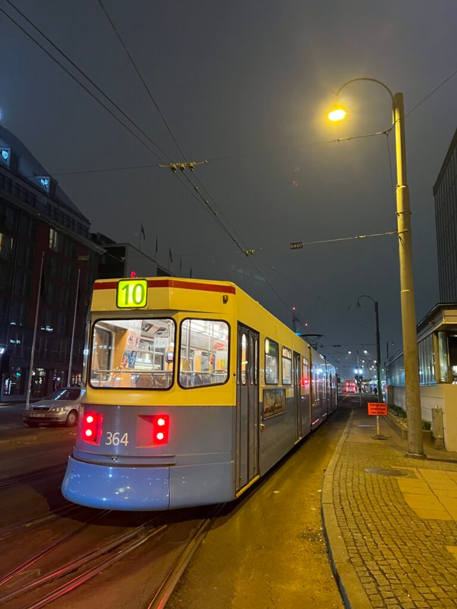 A tram moves through a cityscape at night.