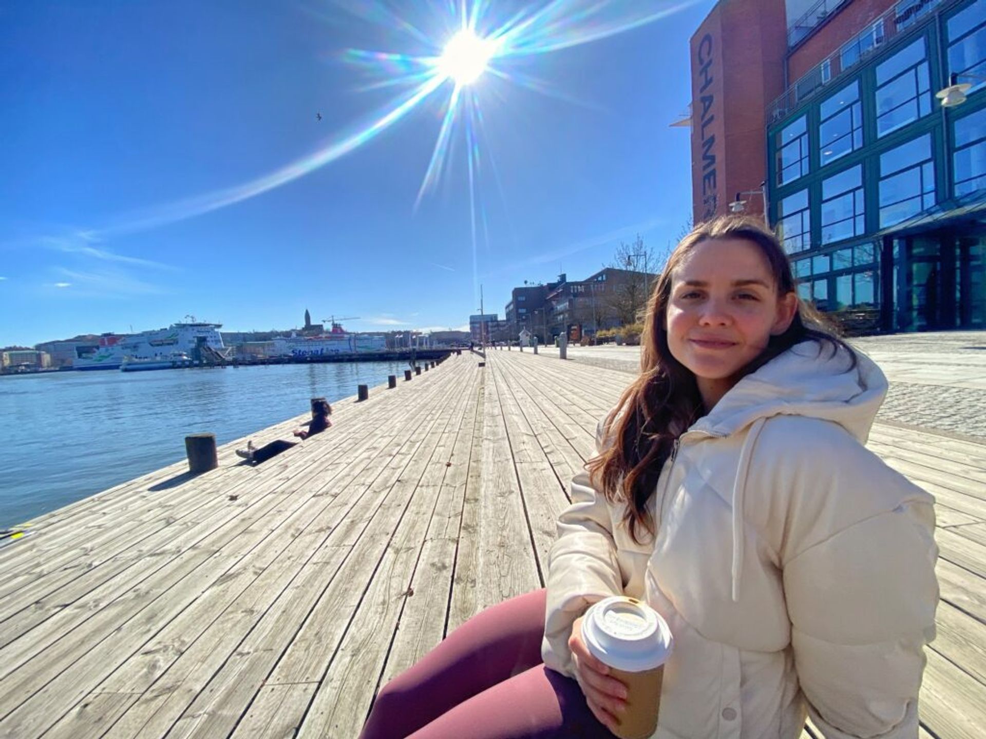 A woman sits leisurely on the steps of a wooden promenade.