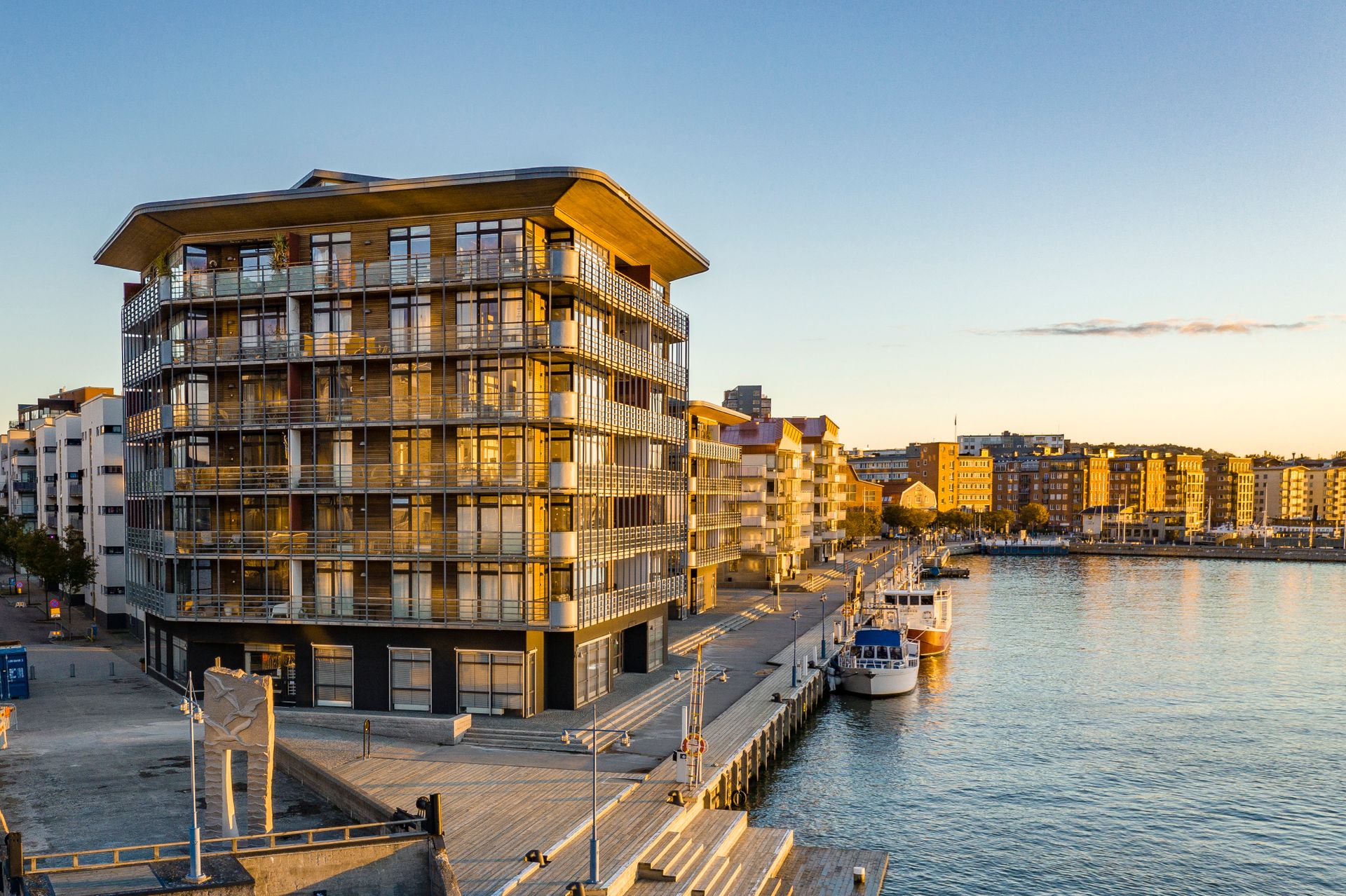 Apartment buildings line the pier, with boats docked nearby.