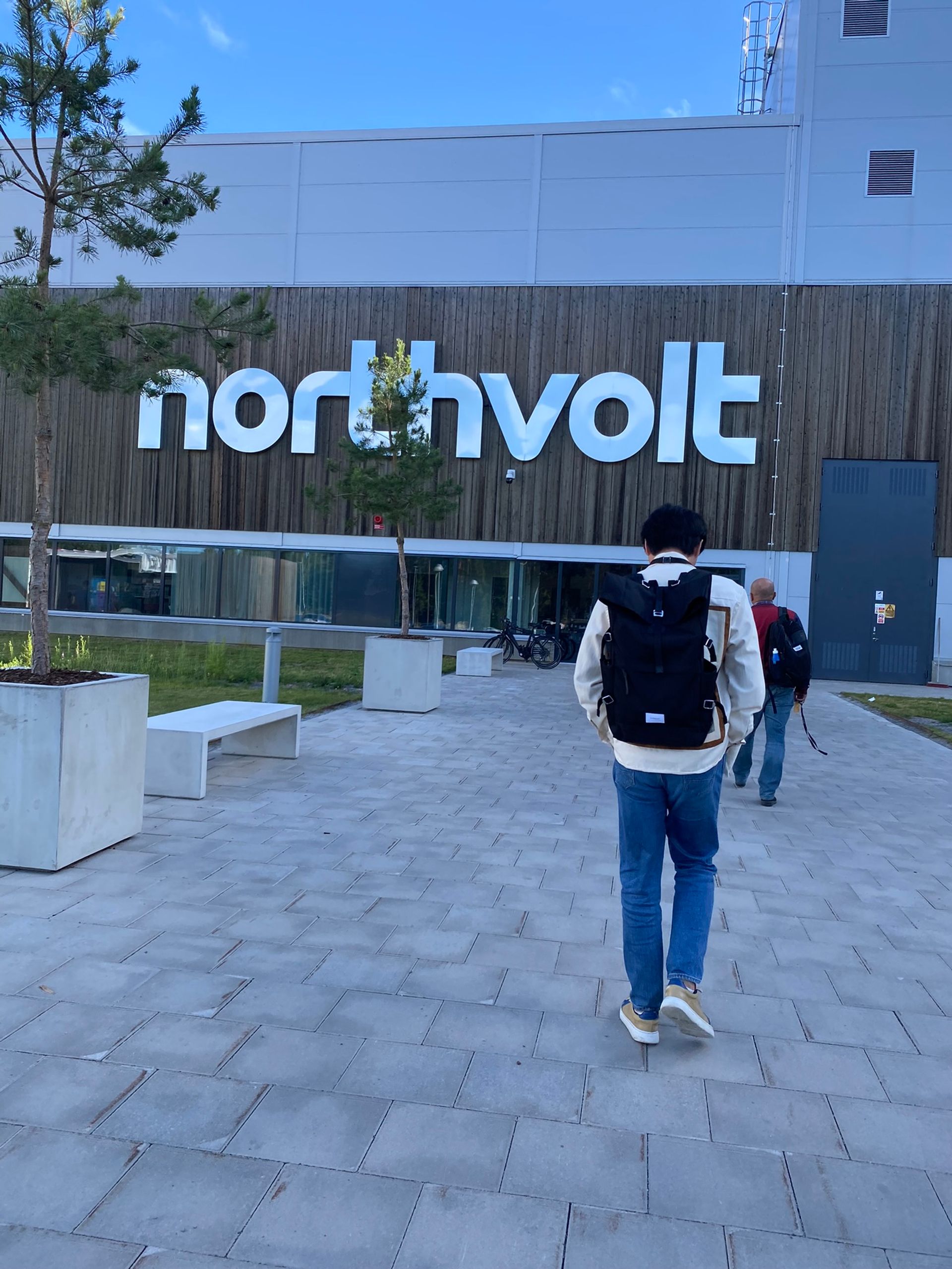 A man walking into a building marked with the Northvolt logo.