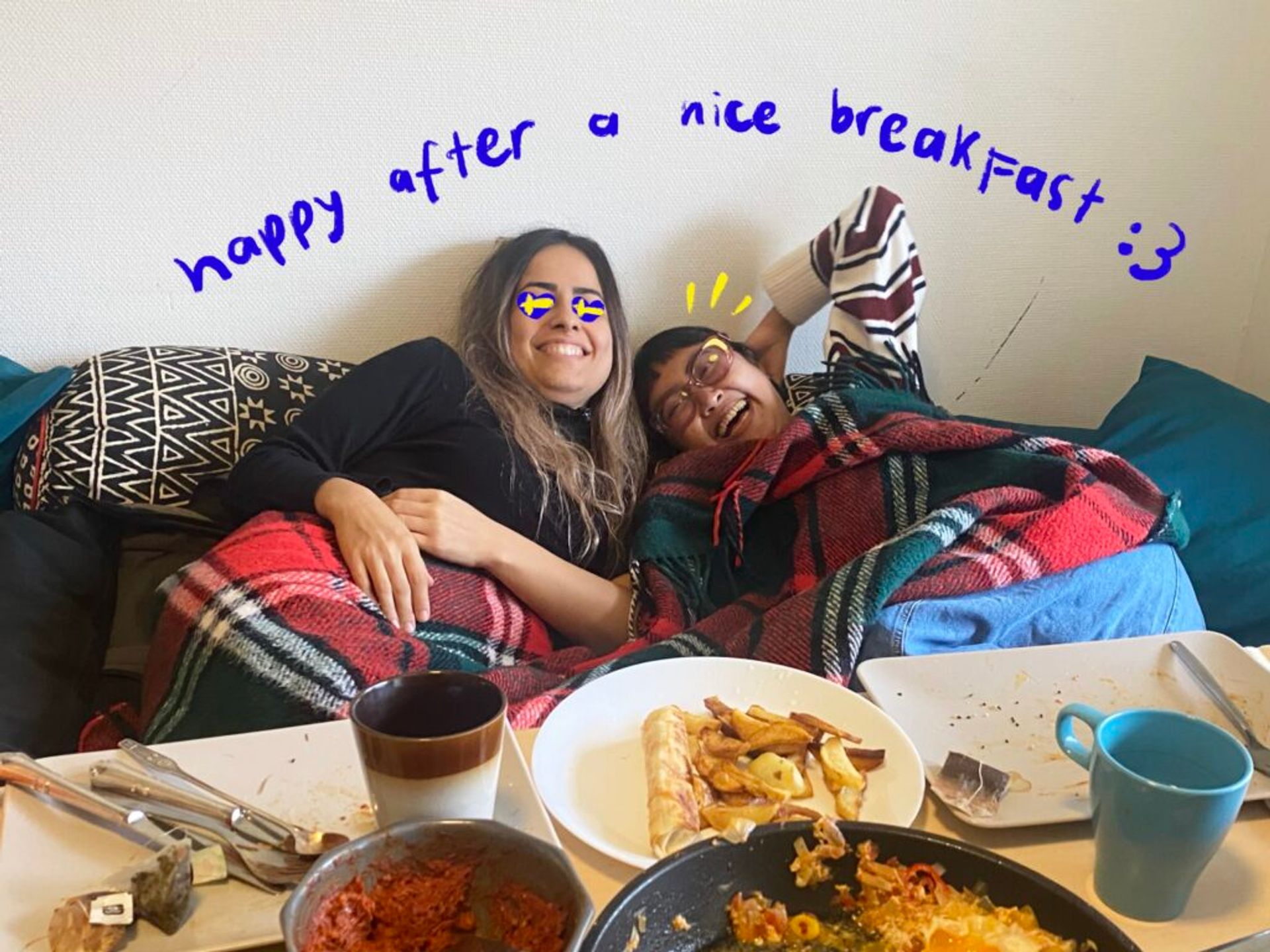 Two friends laughing happily on a sofa after breakfast.