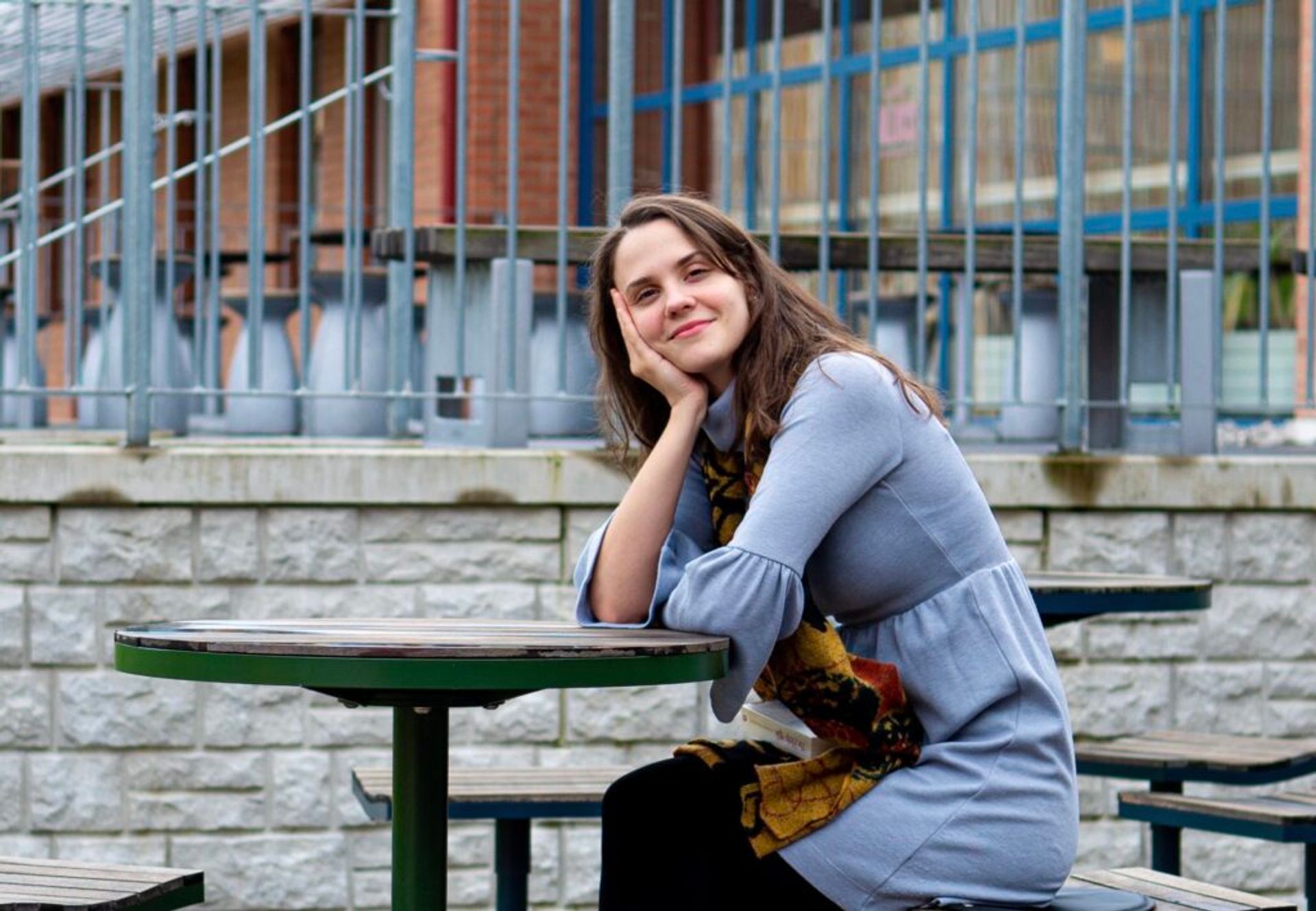 A smiling student sits at a picnic table on Skövde campus.