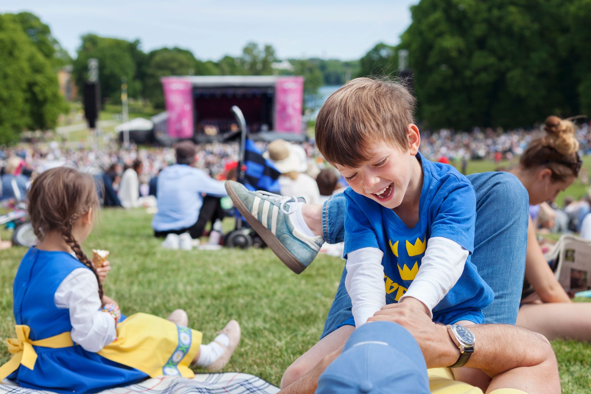 A child playfully interacts with an adult at a music festival.