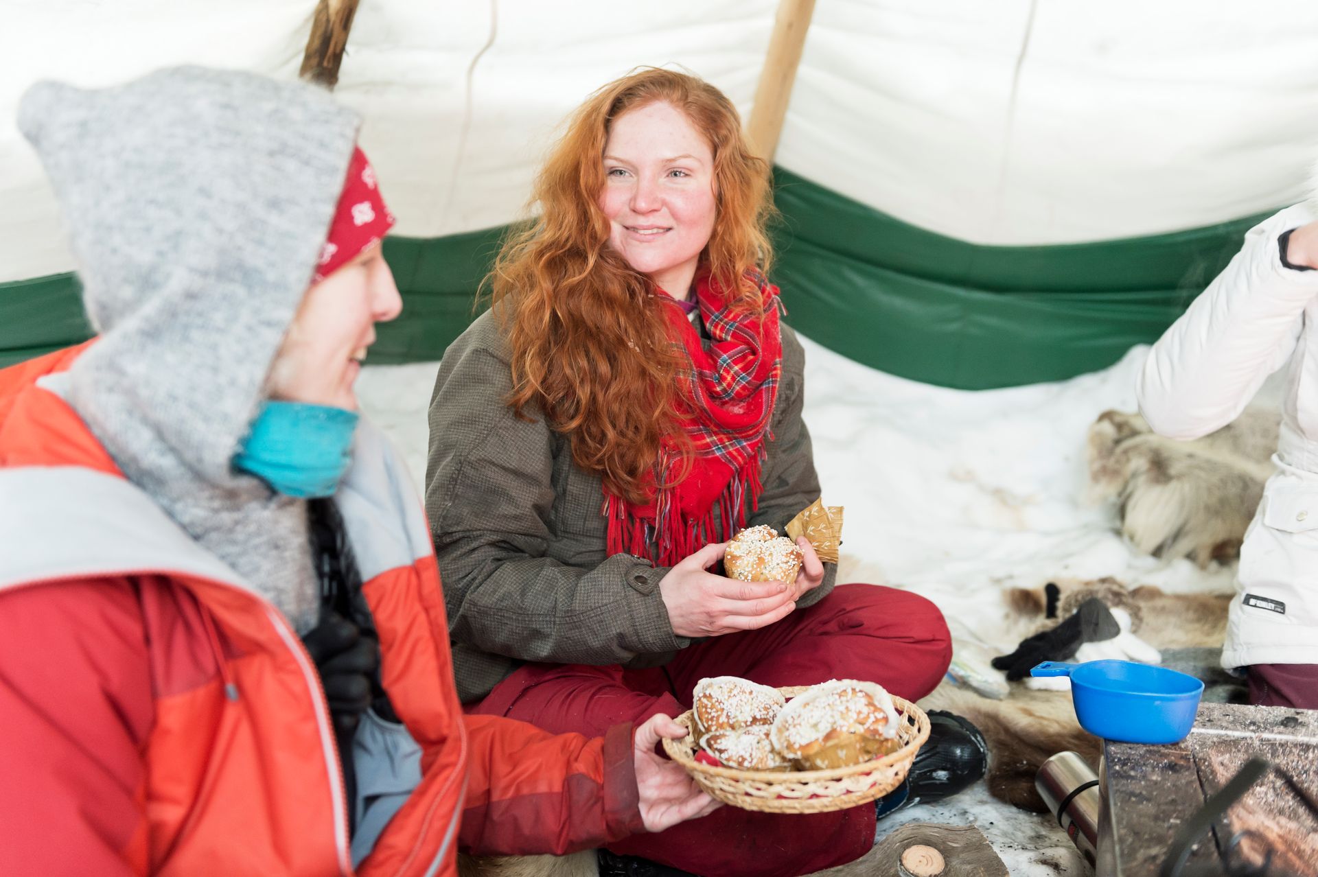 Friends delighting in a traditional Swedish fika inside a cozy tipi during the winter season.