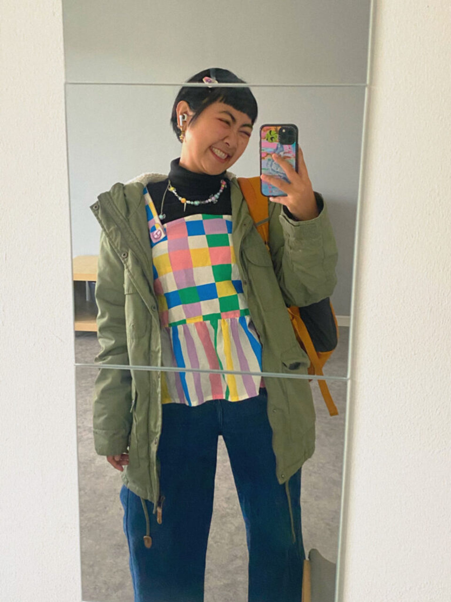 Mirror selfie of an international student in their accommodation, wearing colourful winter clothes.