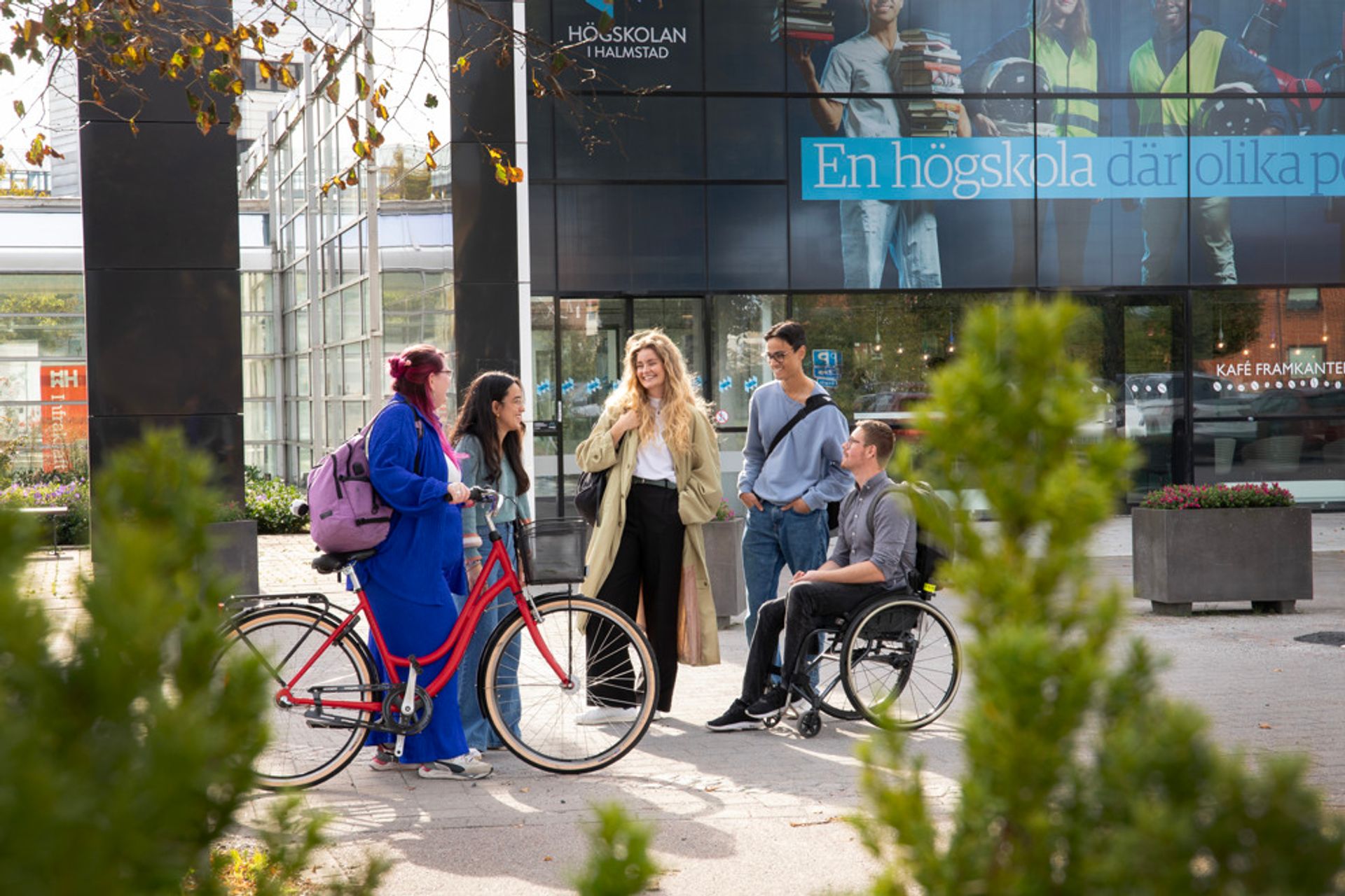 Group of international students standing and chatting outside of a Halmstad University campus building.