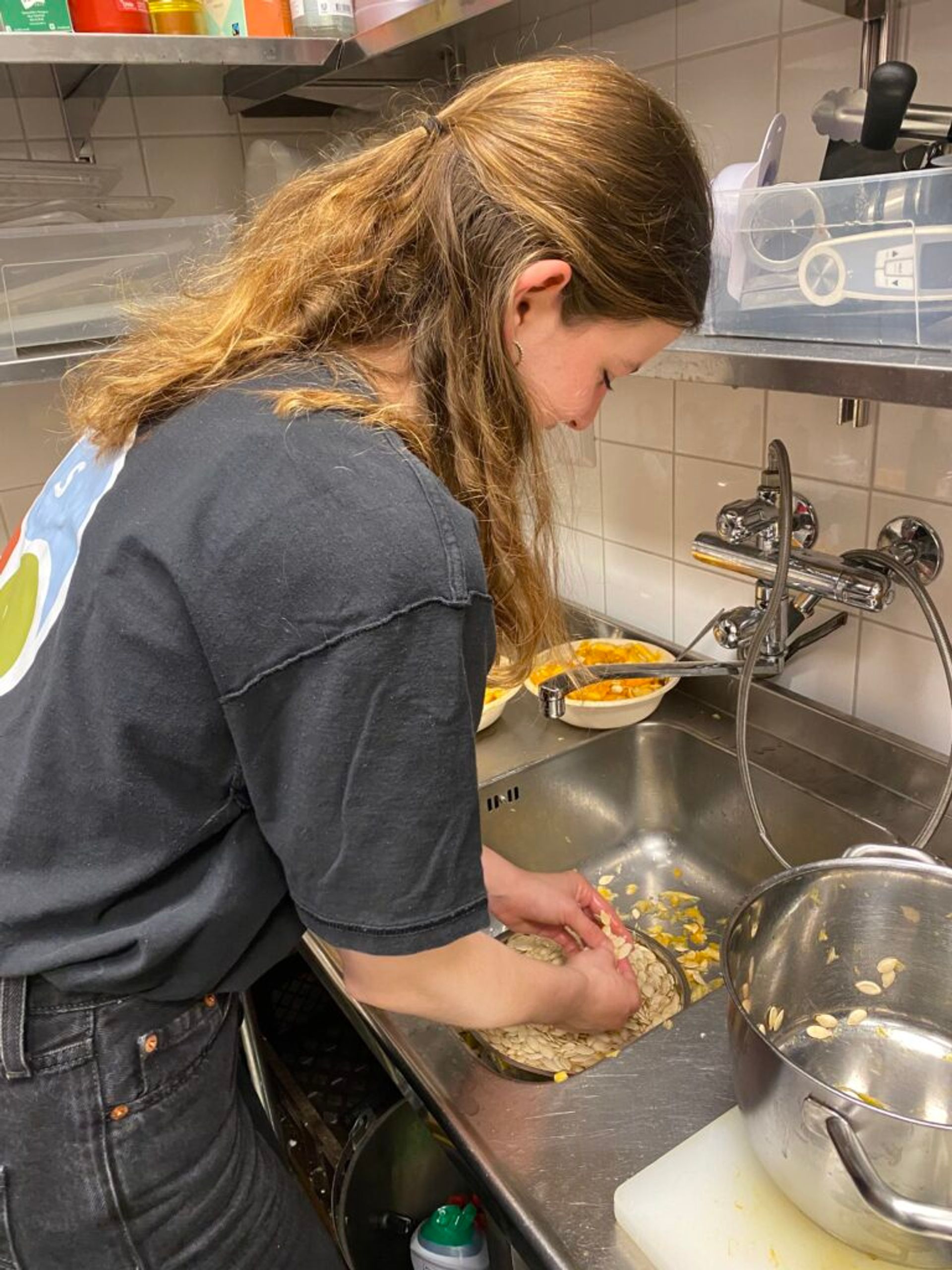 A person cleaning pumpking seeds to be used as garnish.