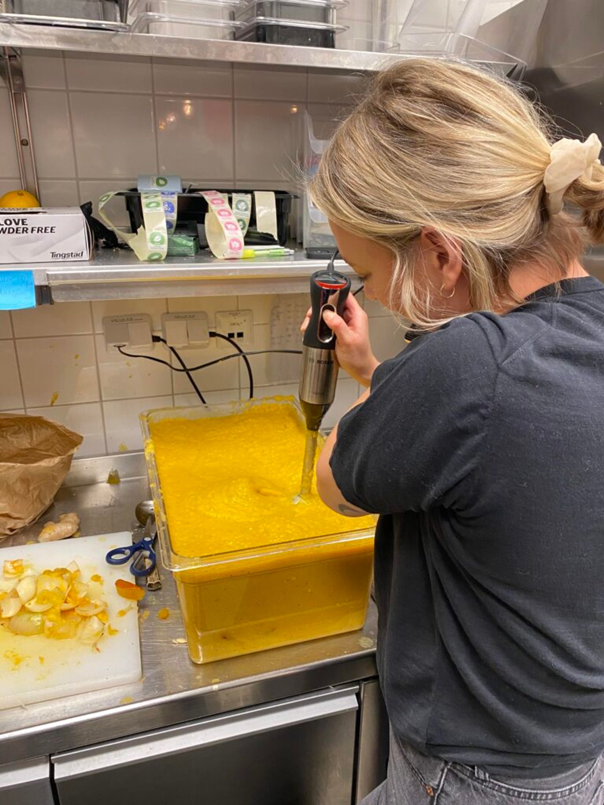 A person using a hand blender to prepare pumpkin soup.