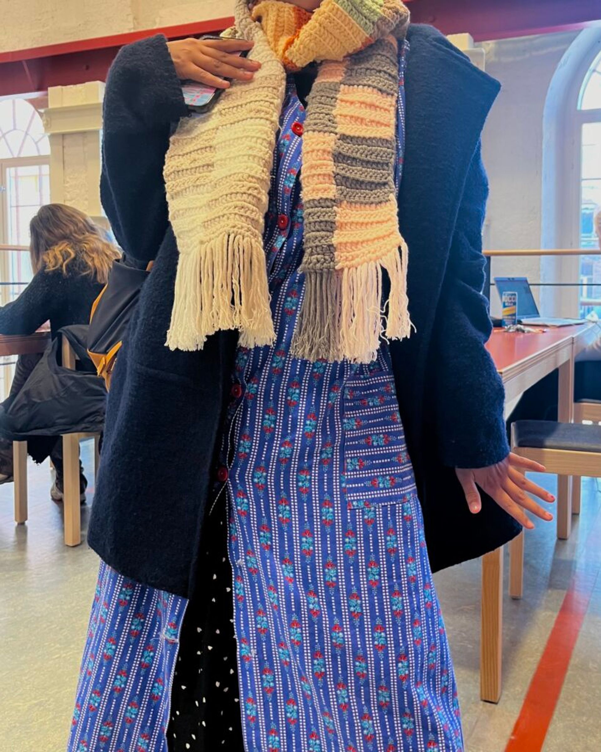 An international student with a colourful, layered outfit in the campus library.