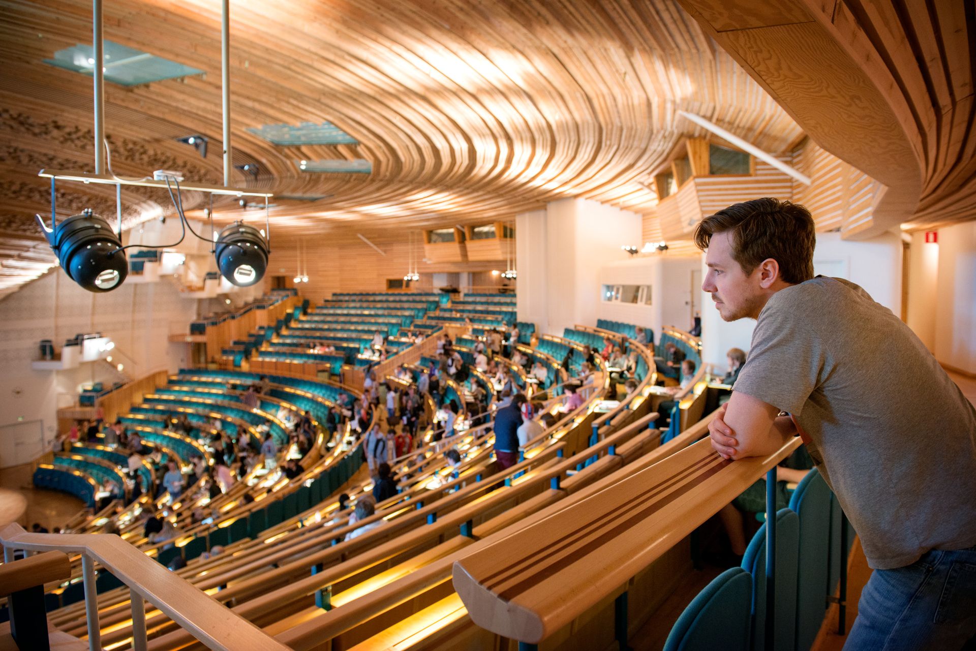 A wood-paneled lecture hall filled with students.