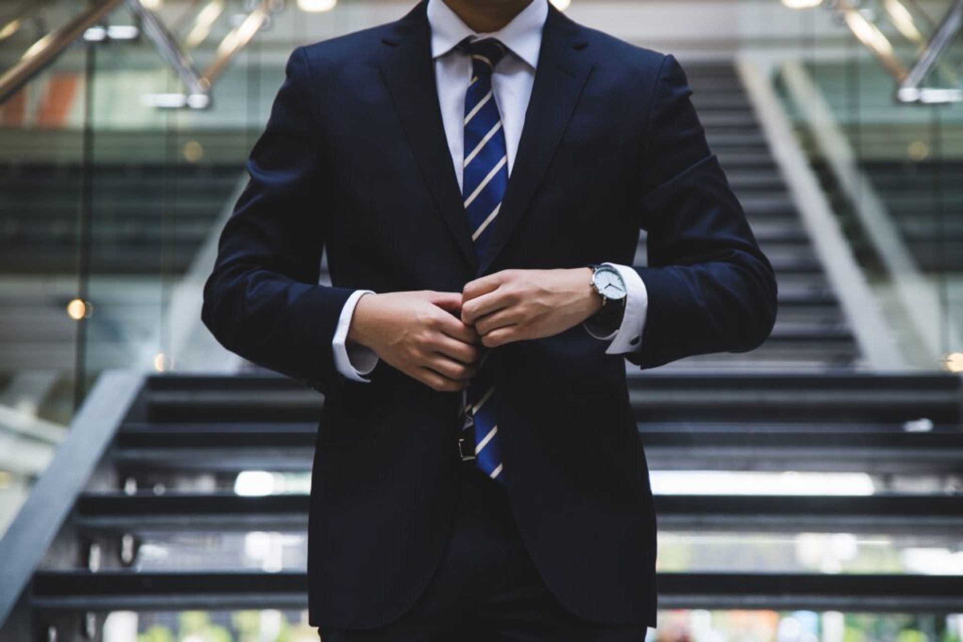 A close-up of a person buttoning up a suit.