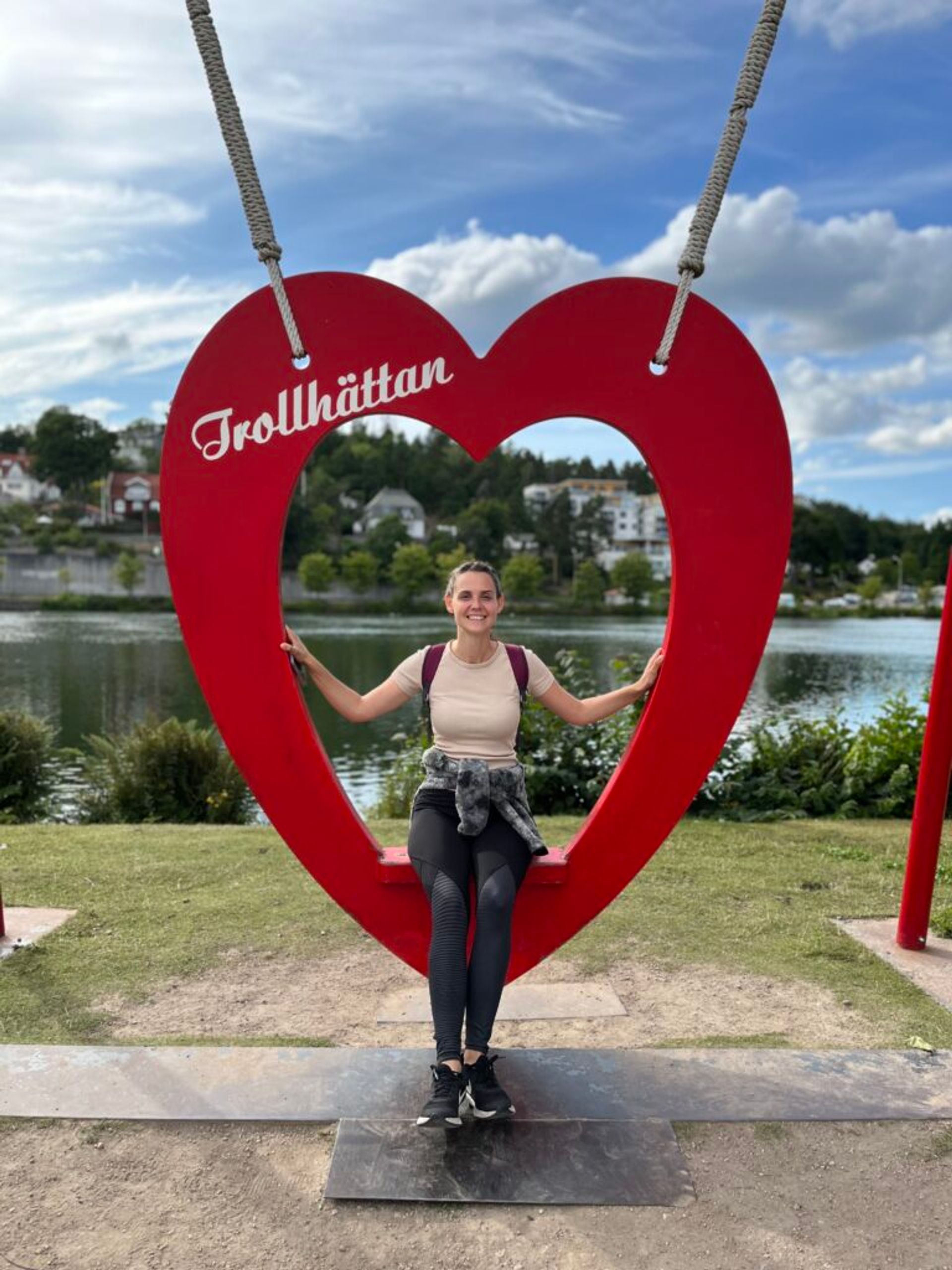 Girl sitting on a heart-shaped swing with the sign 'Trollhättan'