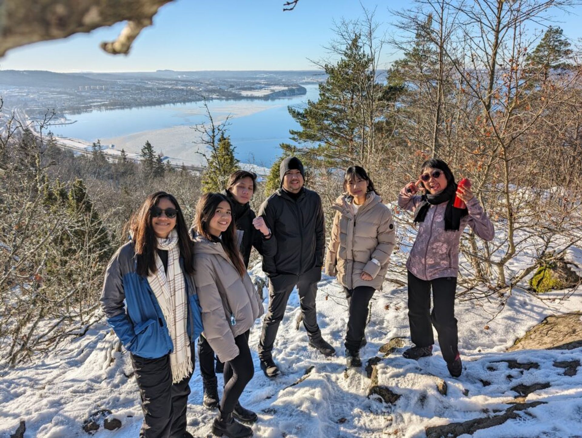 A group of international students from Indonesia posing on a snowy hill while on a hike in Jönköping, Sweden.