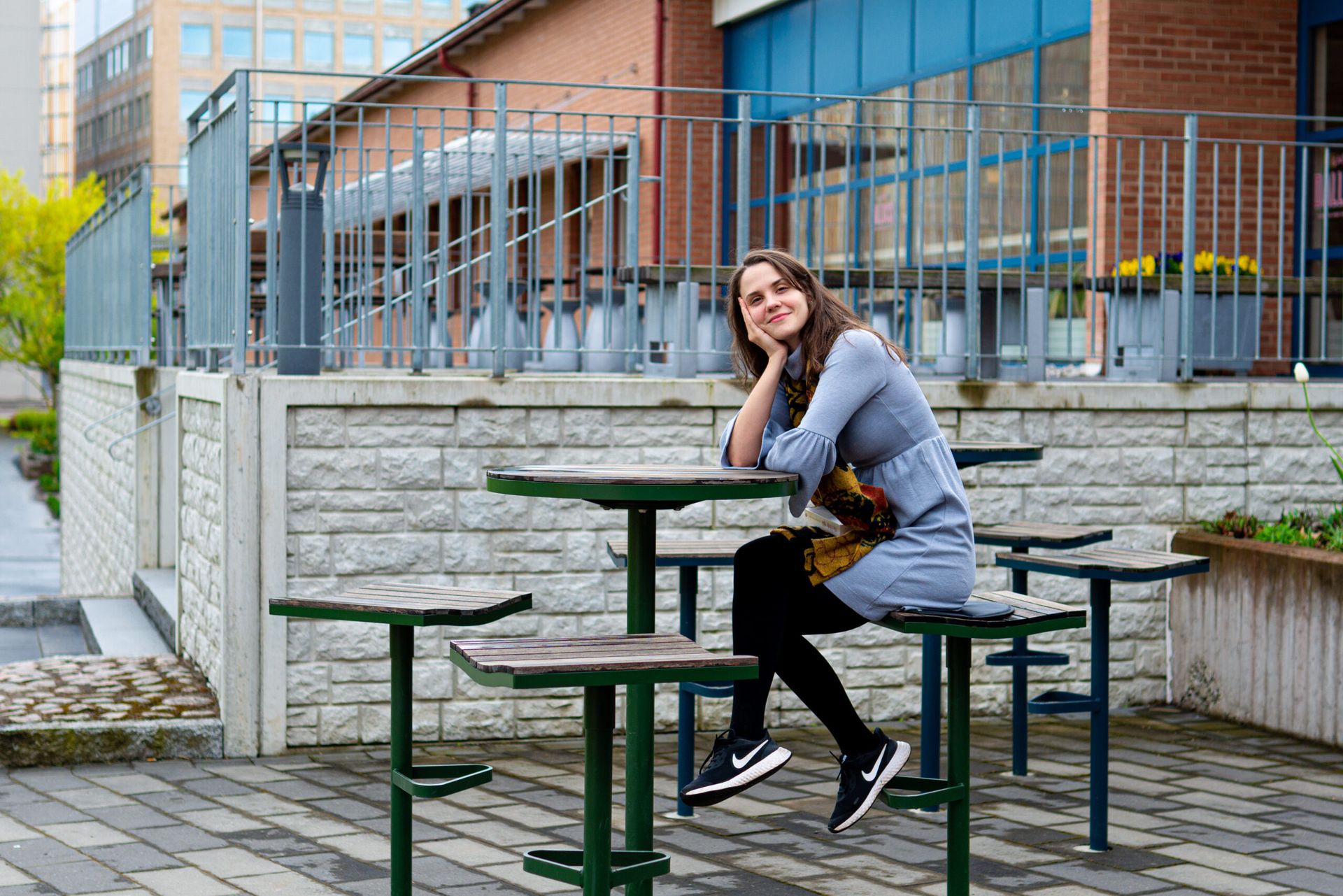 A woman sitting on a chair outdoors at a university campus.