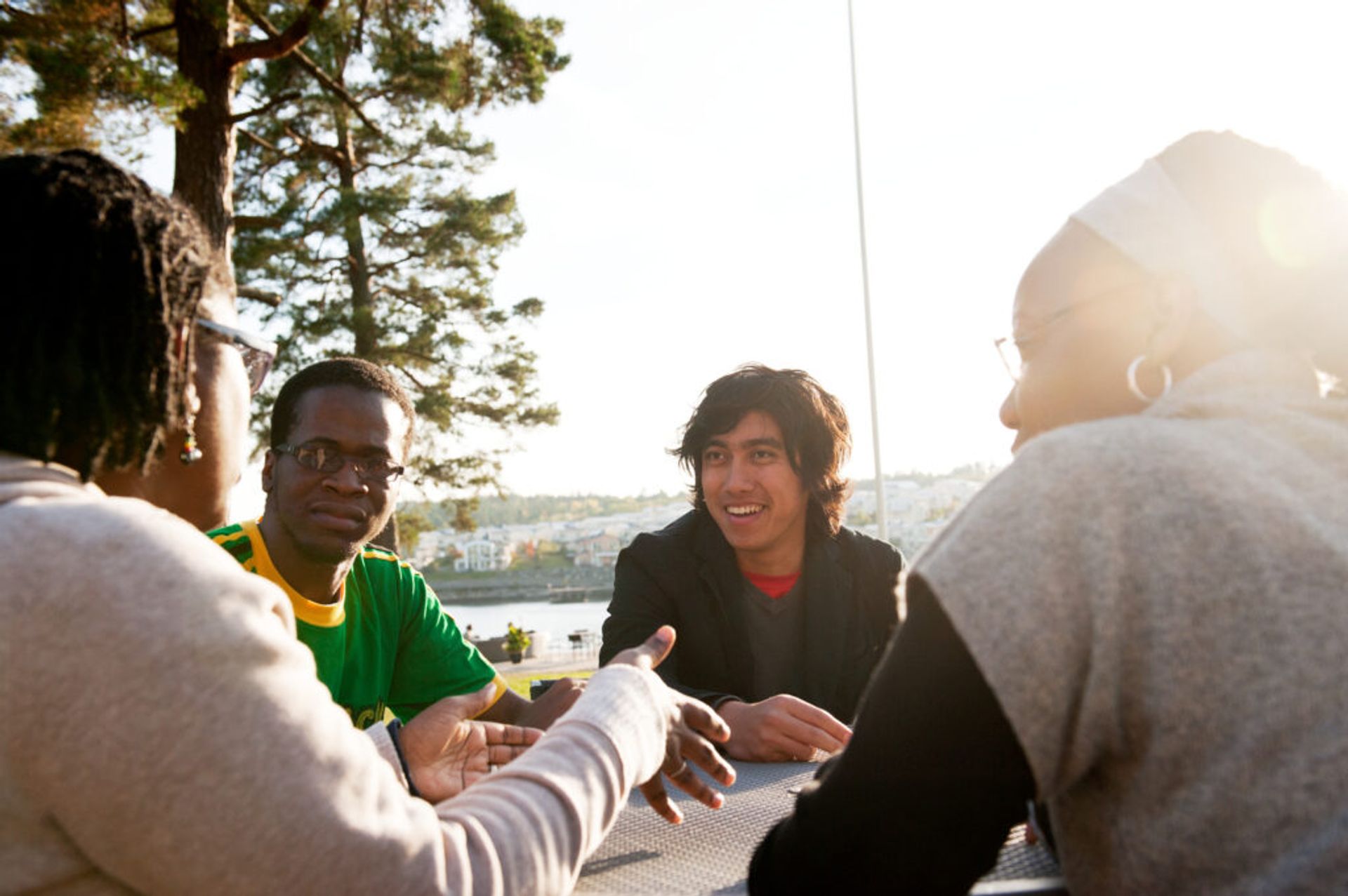 A group of international people in Sweden sitting at a table outdoors and hanging out.