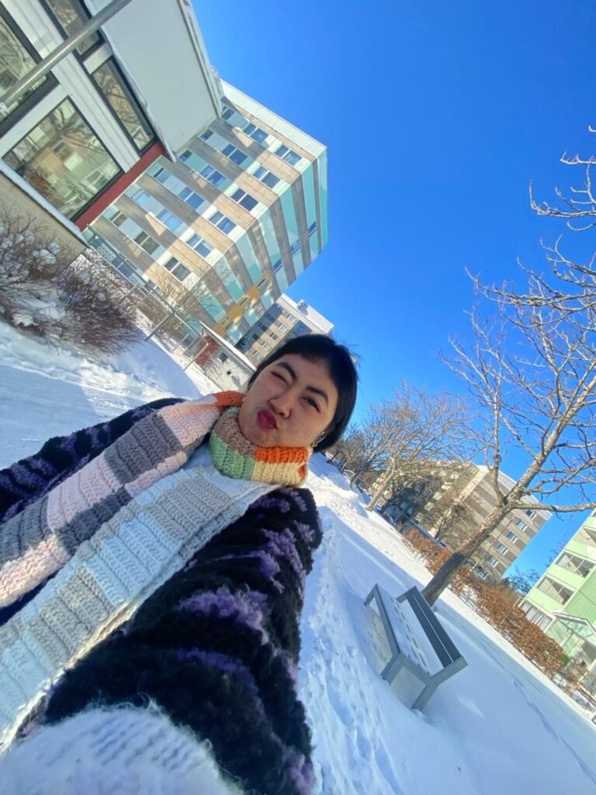 A selfie of an international student walking around a Swedish neighborhood in the snow.