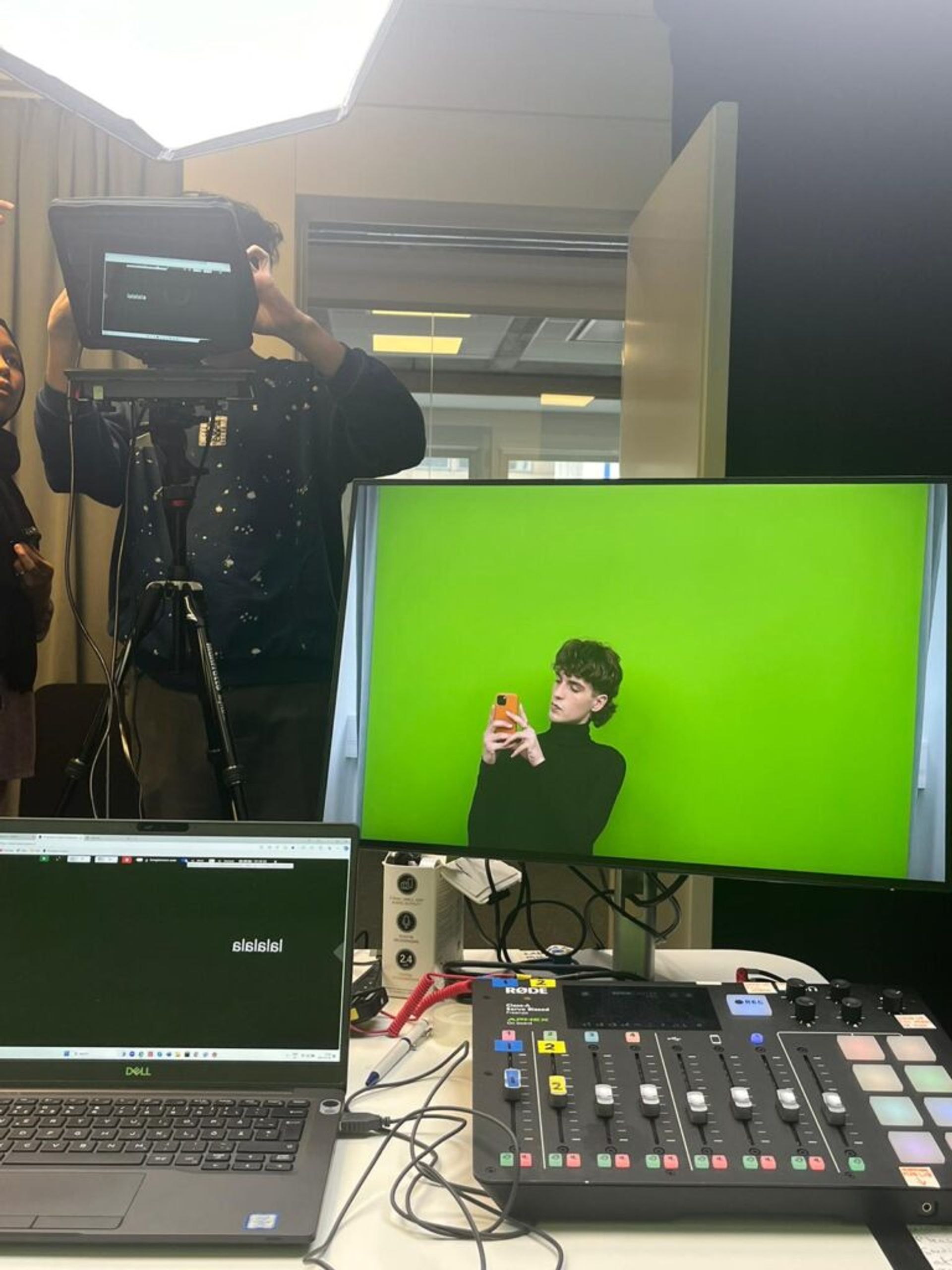 an international student in an office studio in front of a green screen, doing live stream