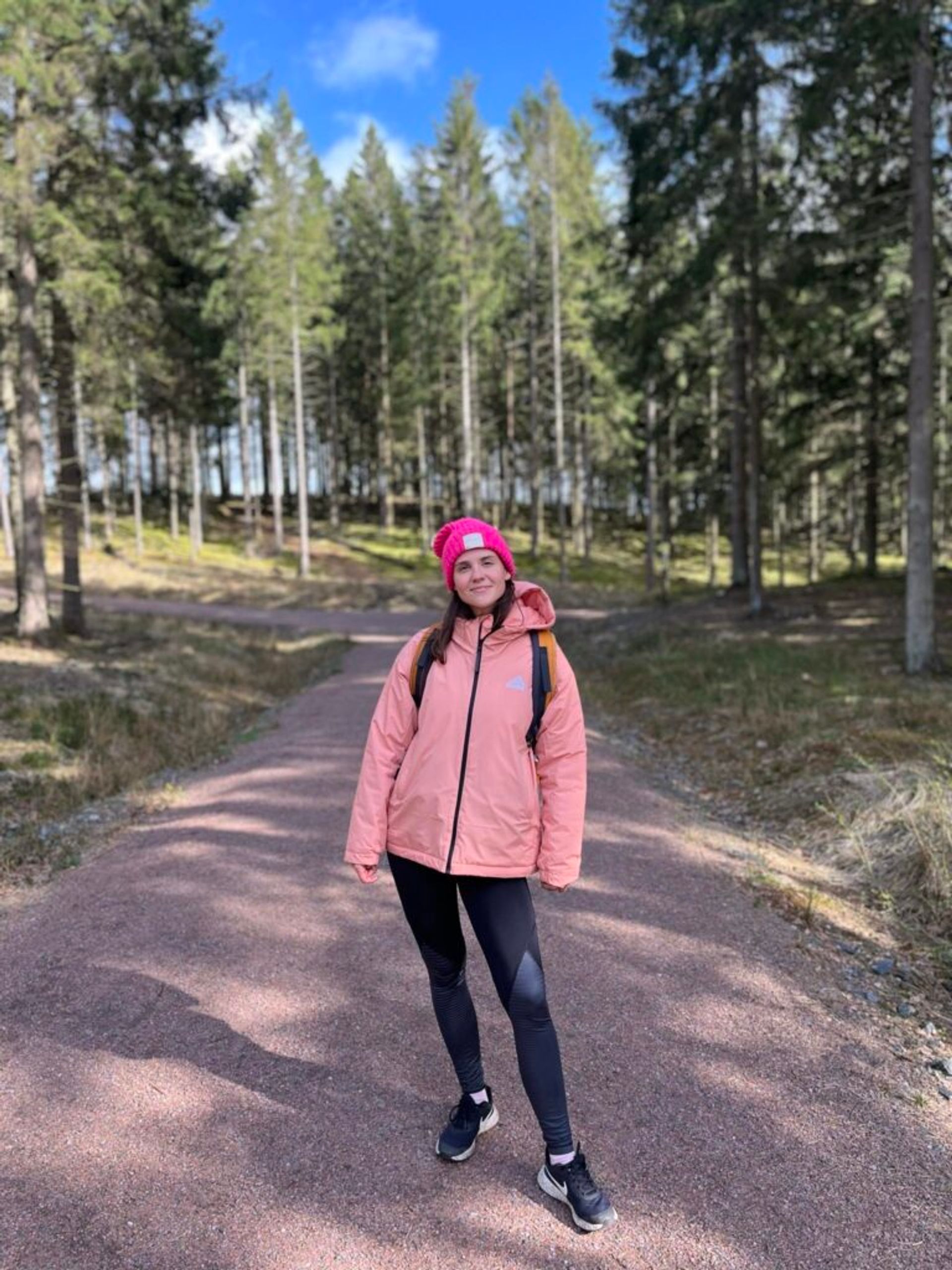 A girl wearing a winter jacket standing in a forest.