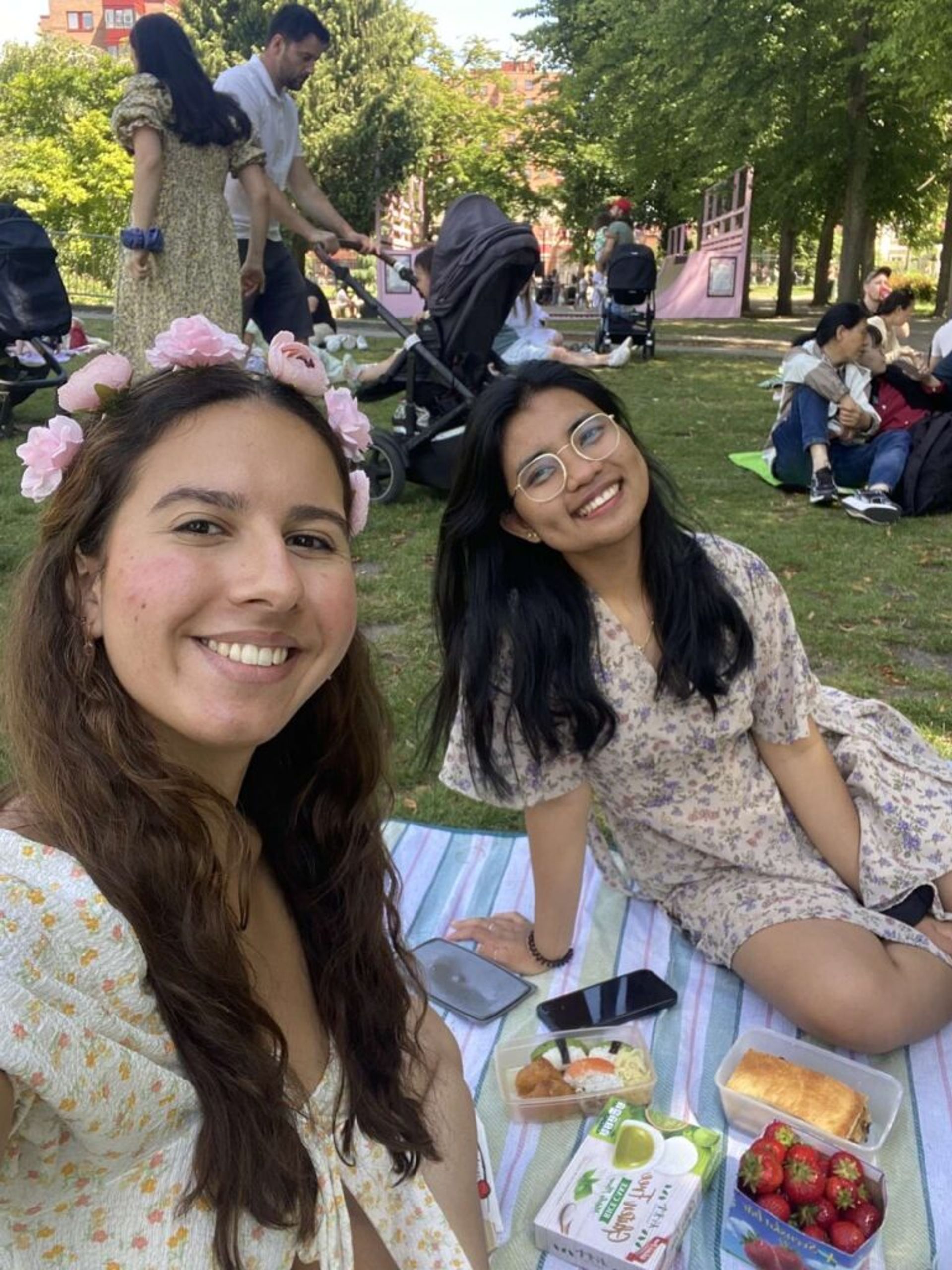 Two girls on a picnic wearing floral dress and taking a selfie. 