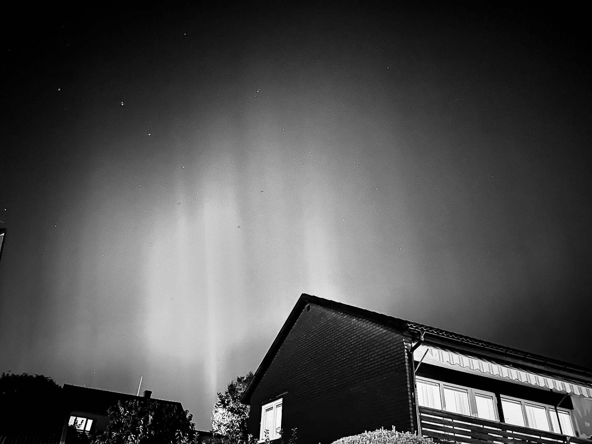 a black and white image of auroras, highlighting the shape of beams