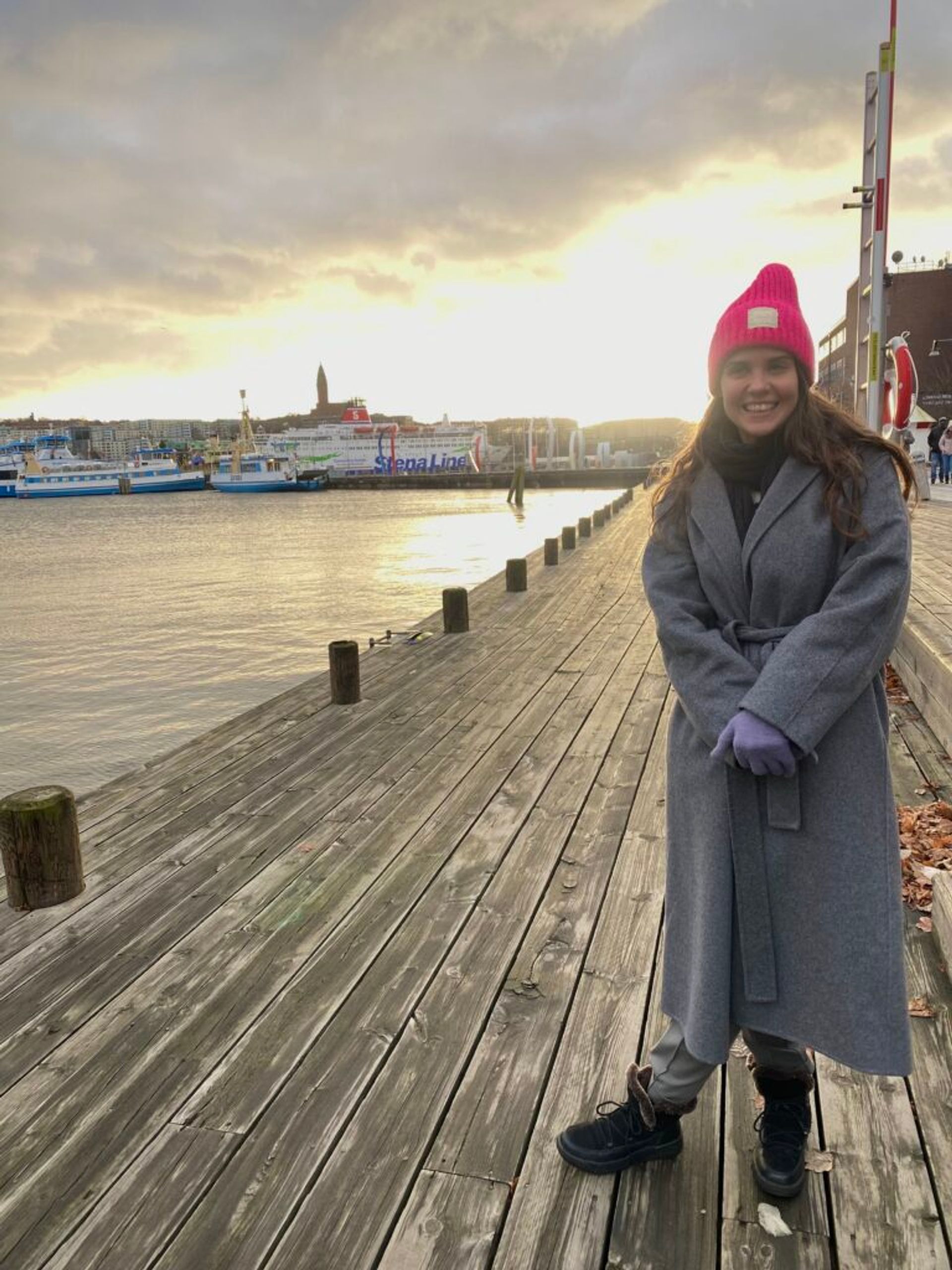 A girl smiling by in a harbour by a sunset