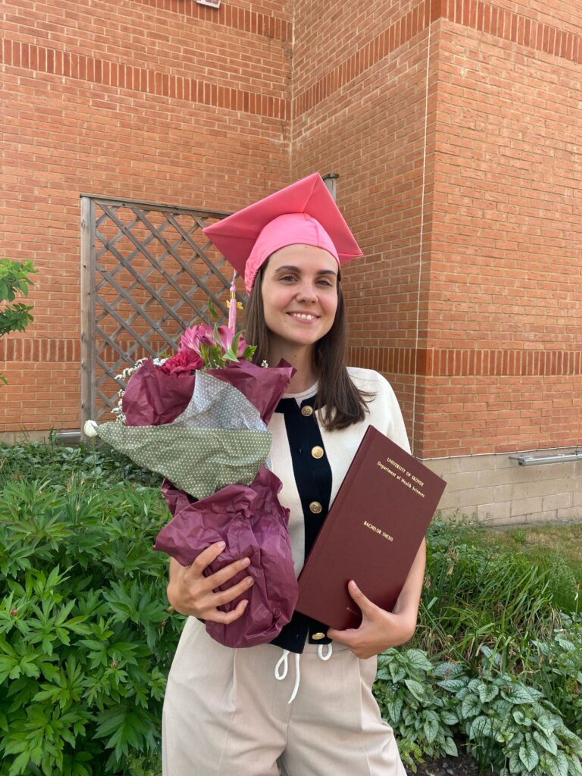 A girl in a graduation hat holding flowers.