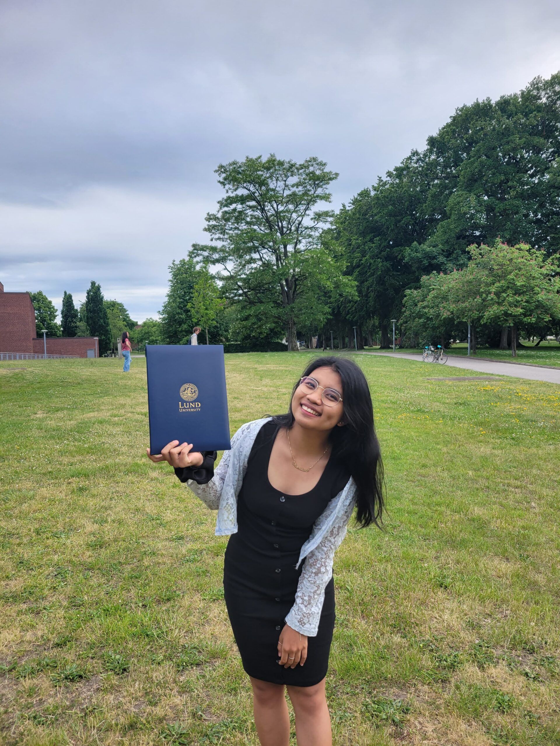 A girl standing outside showing her Lund University folder