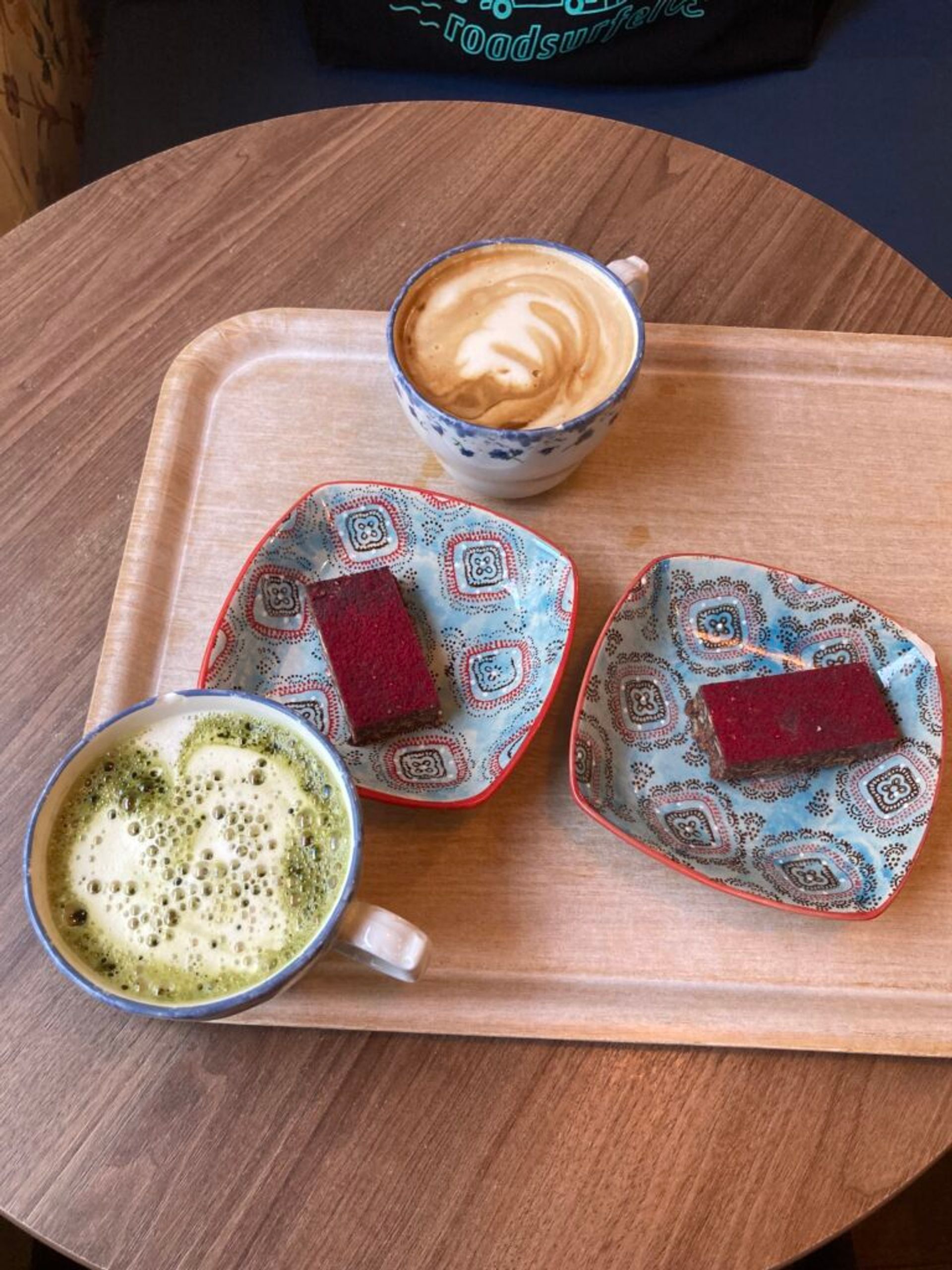 Matcha latte, coffee, and two cakes on a table.