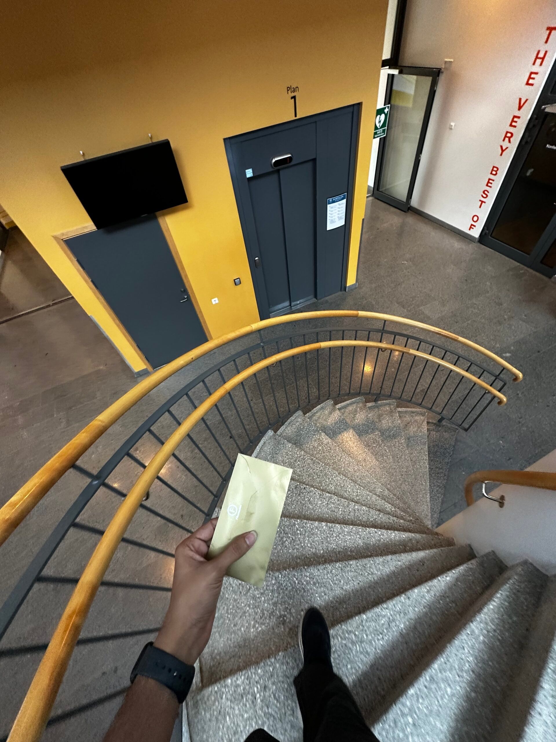 A student climbing down some stairs with a gold envelop is his hands