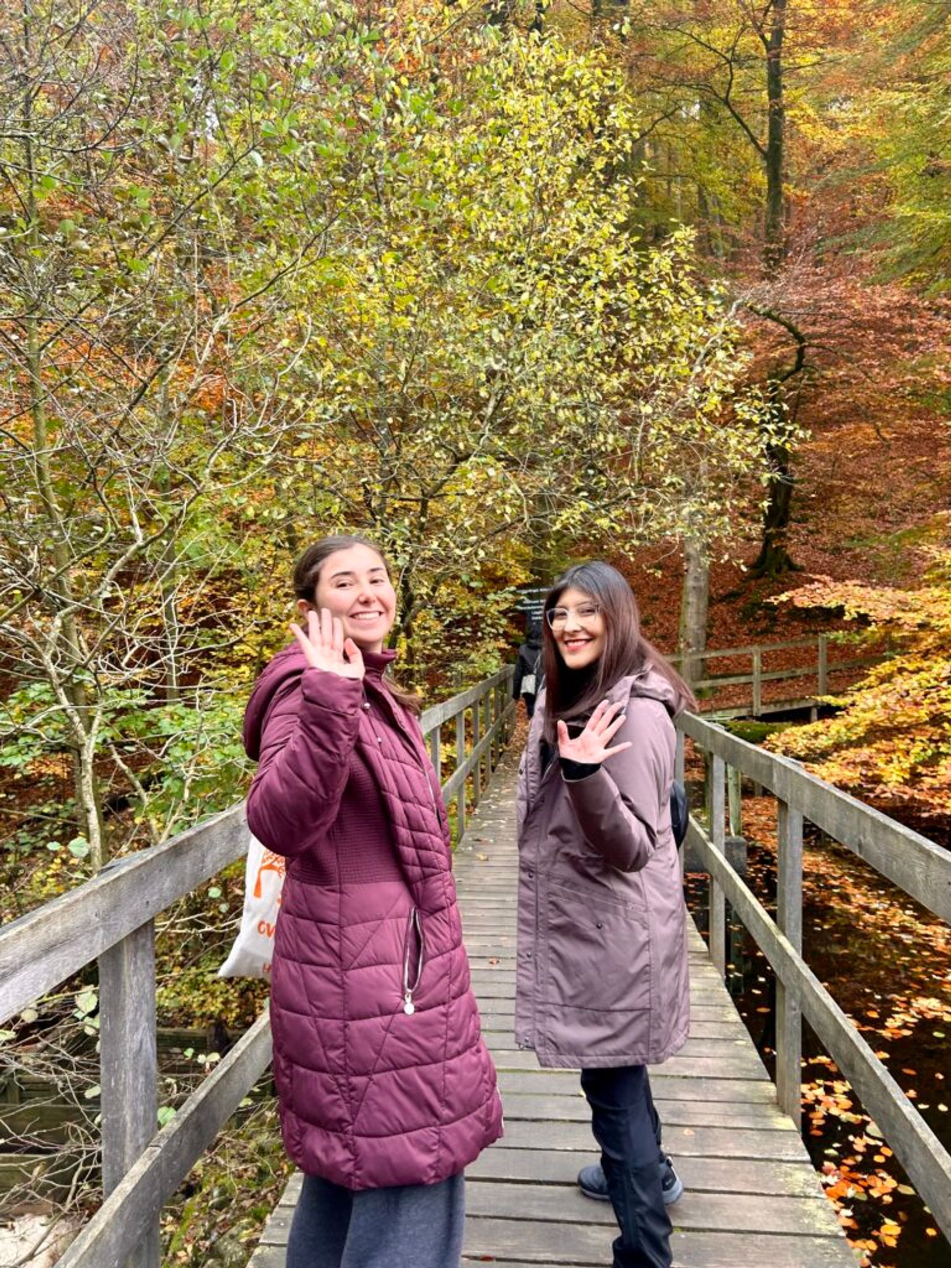 Two girls smiling for the camera in a road in the middle of autumn.