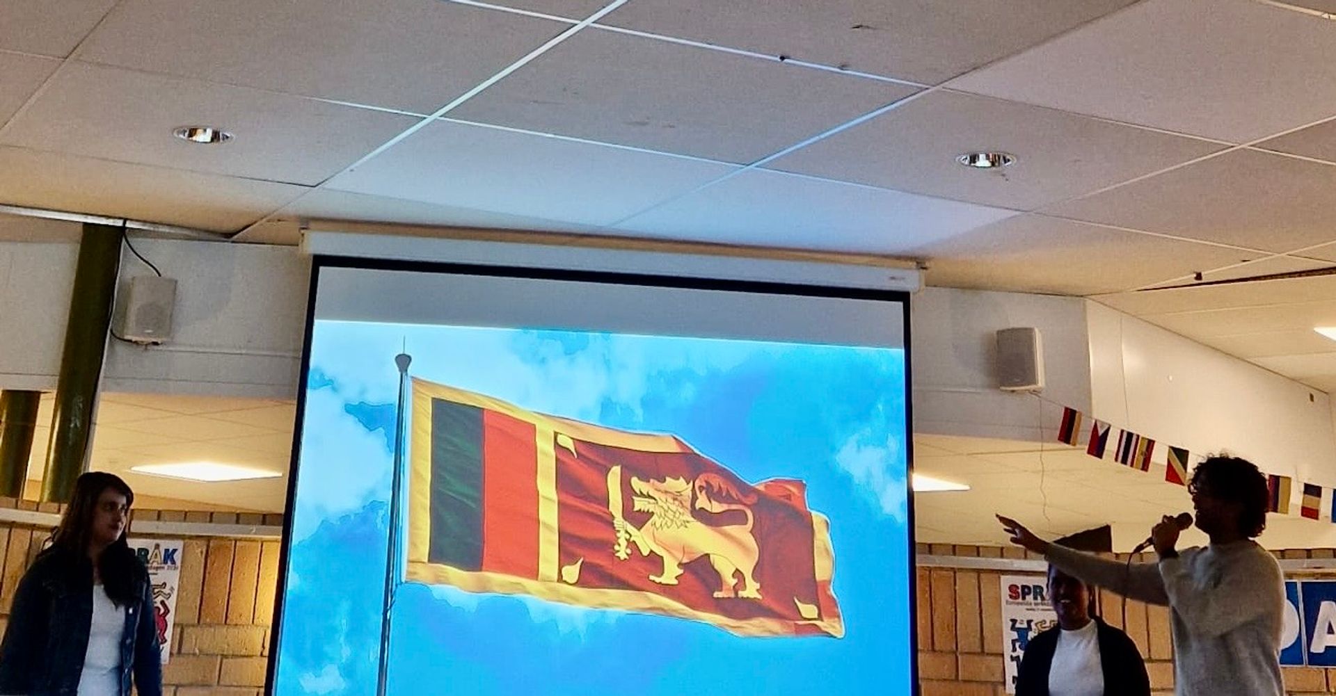 3 student presenting a presentation with the Sri Lankan flag on screen