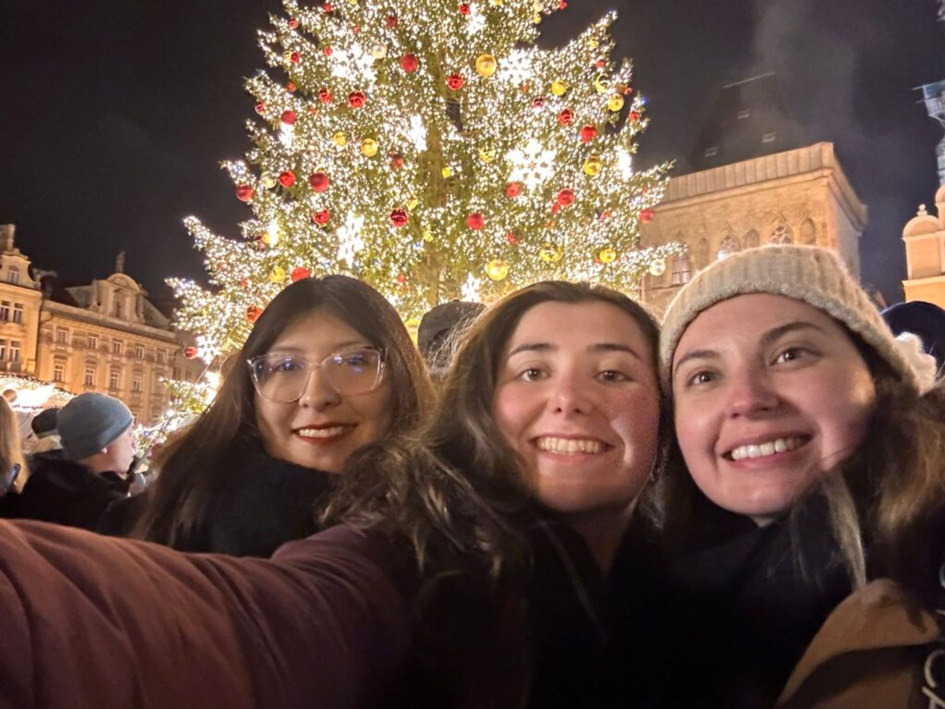 Three friends taking a selfie in front of a Christmas tree