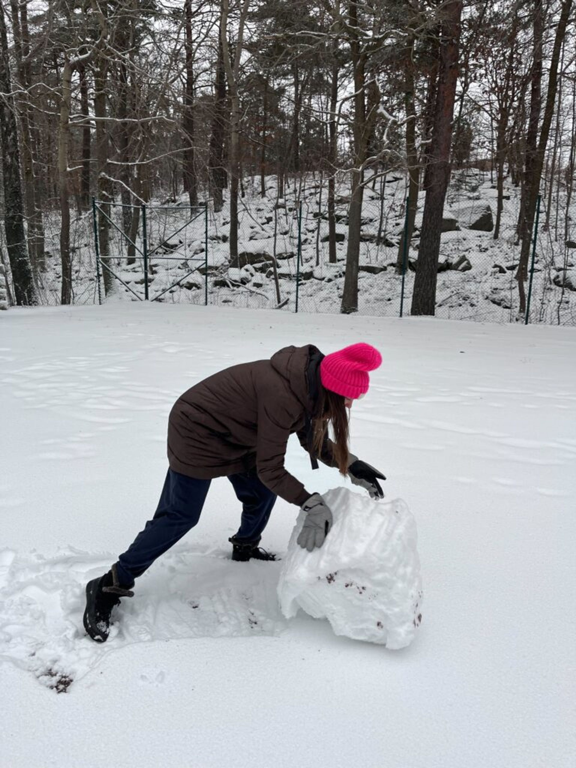 A girl rolling a snowball.