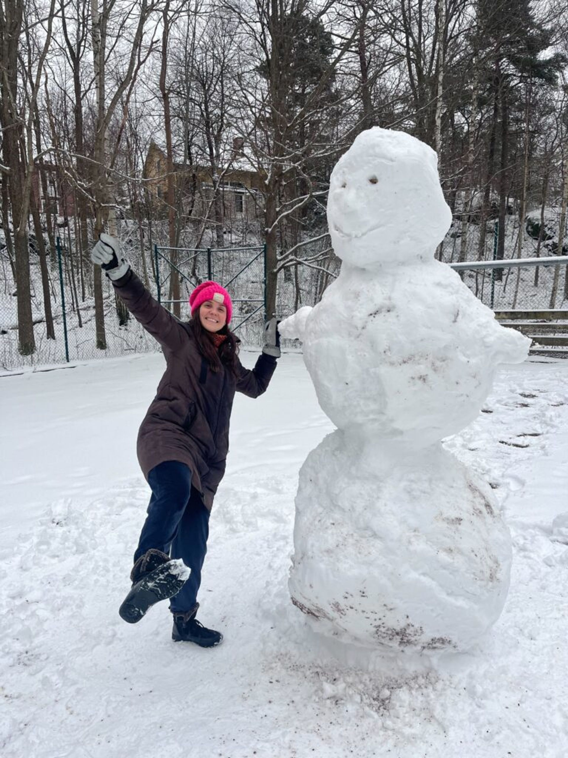 A girl next to a large snowman.