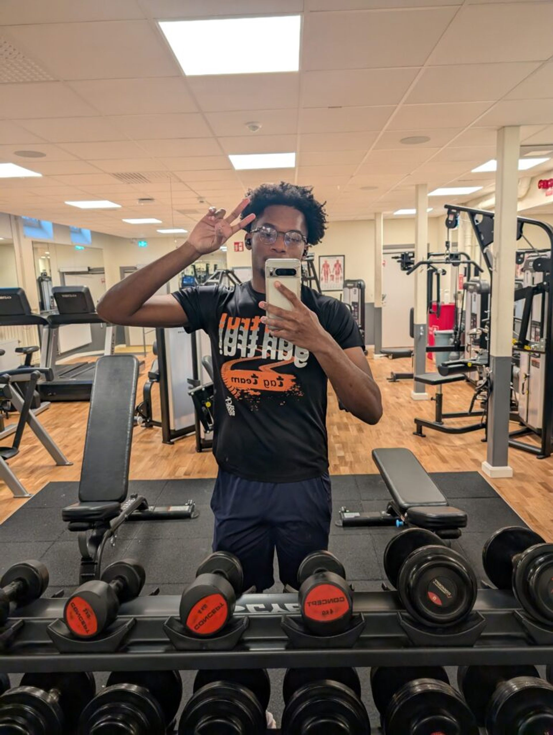 A picture of Joshua posing in the gym mirror with all the gym equipment in the background. 