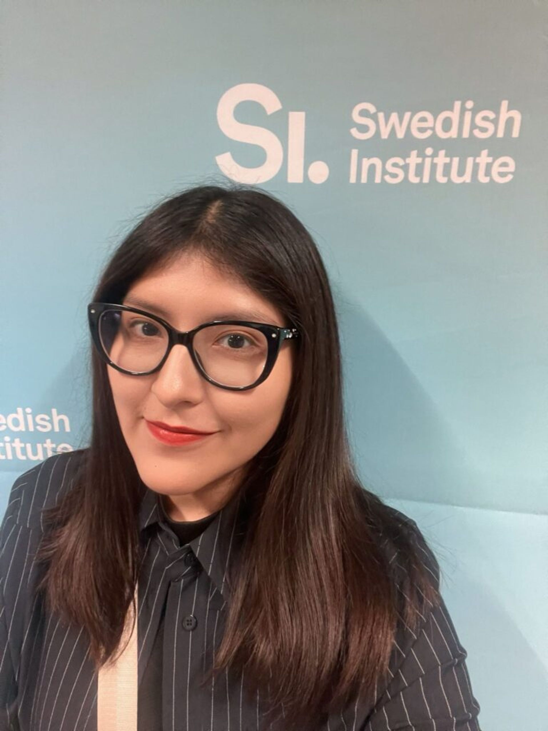 A girl posing for a picture with a panel of the Swedish Institute