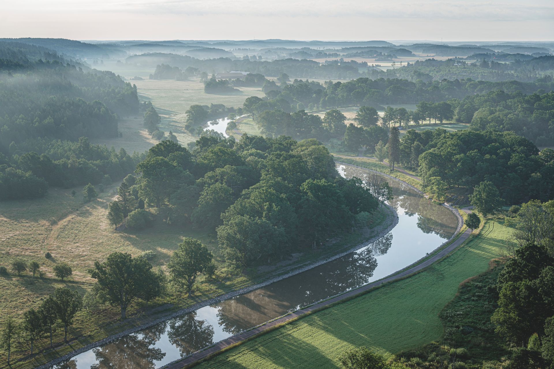 A canal winds through a green landscape.