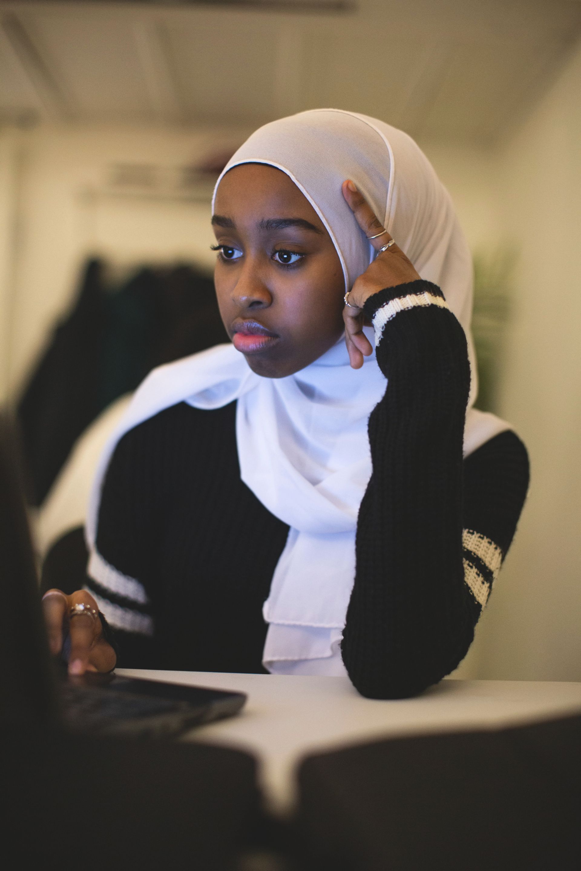 A young woman with a veil works in front of the computer.