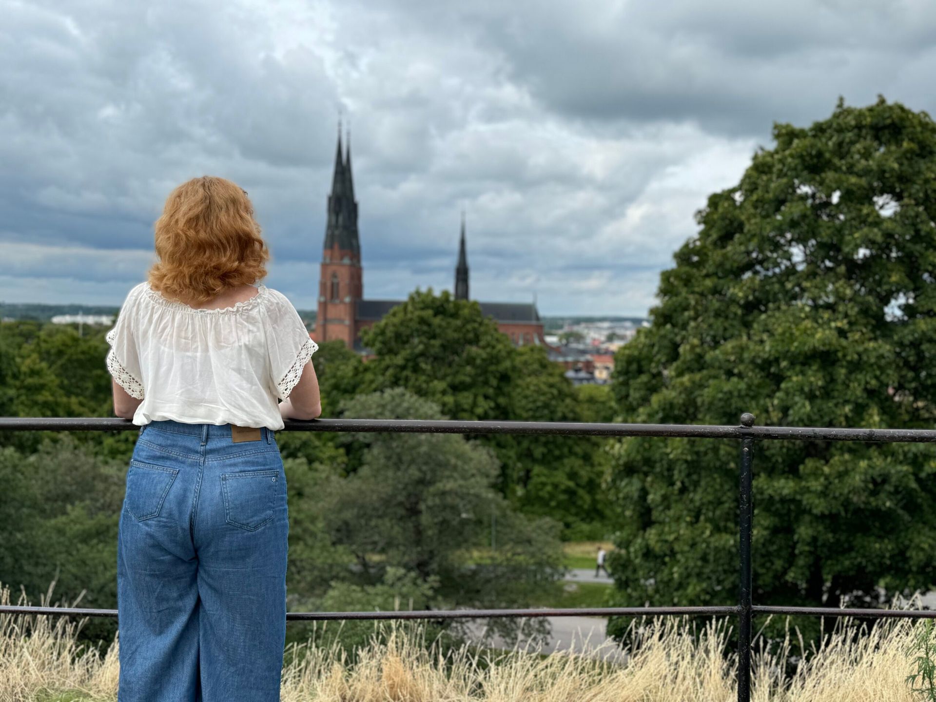 A back shot of a girl looking at the Uppsala skyline with the cathedral visible