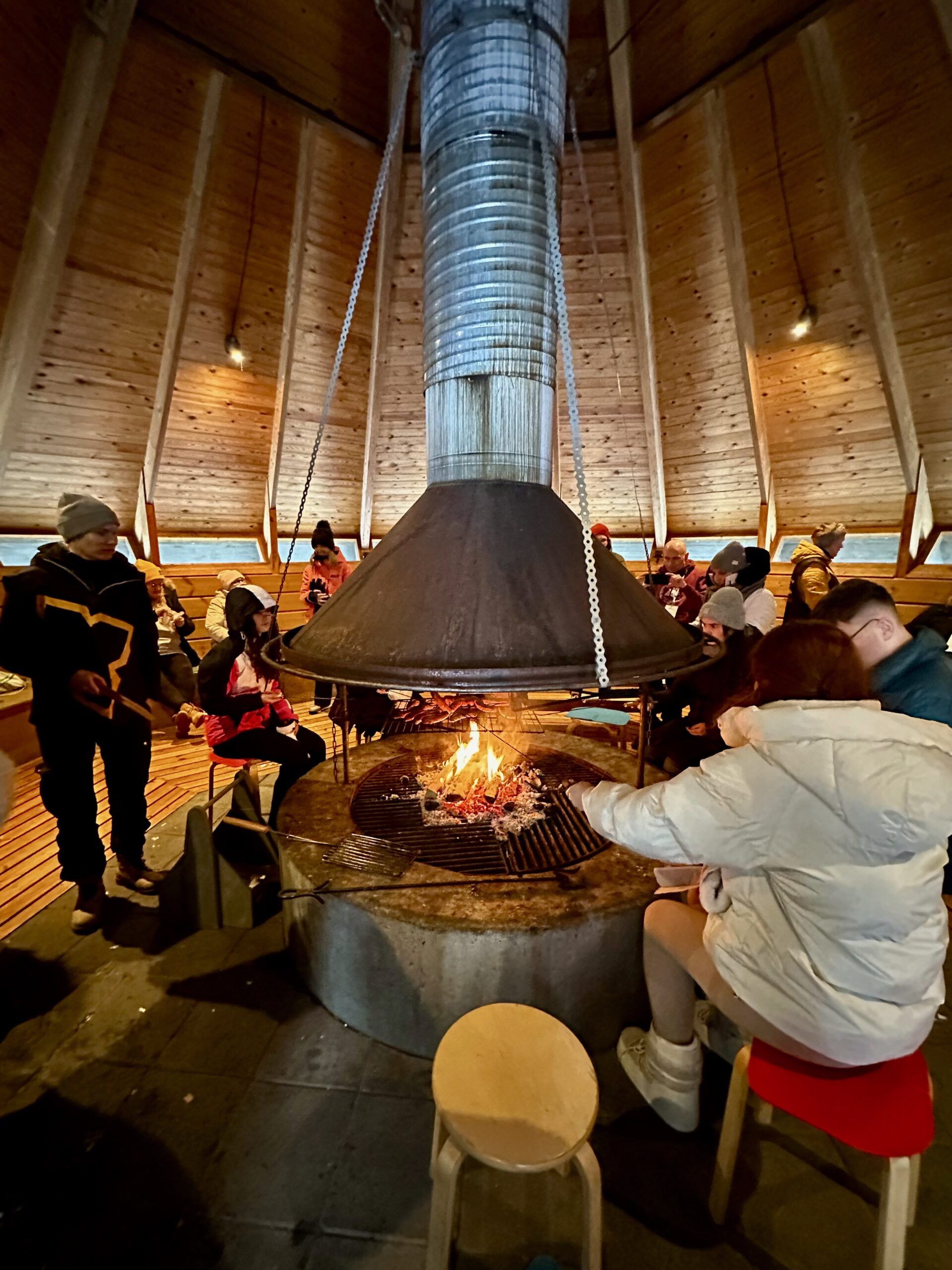 a group of students surrounding a fire and cooking sausages