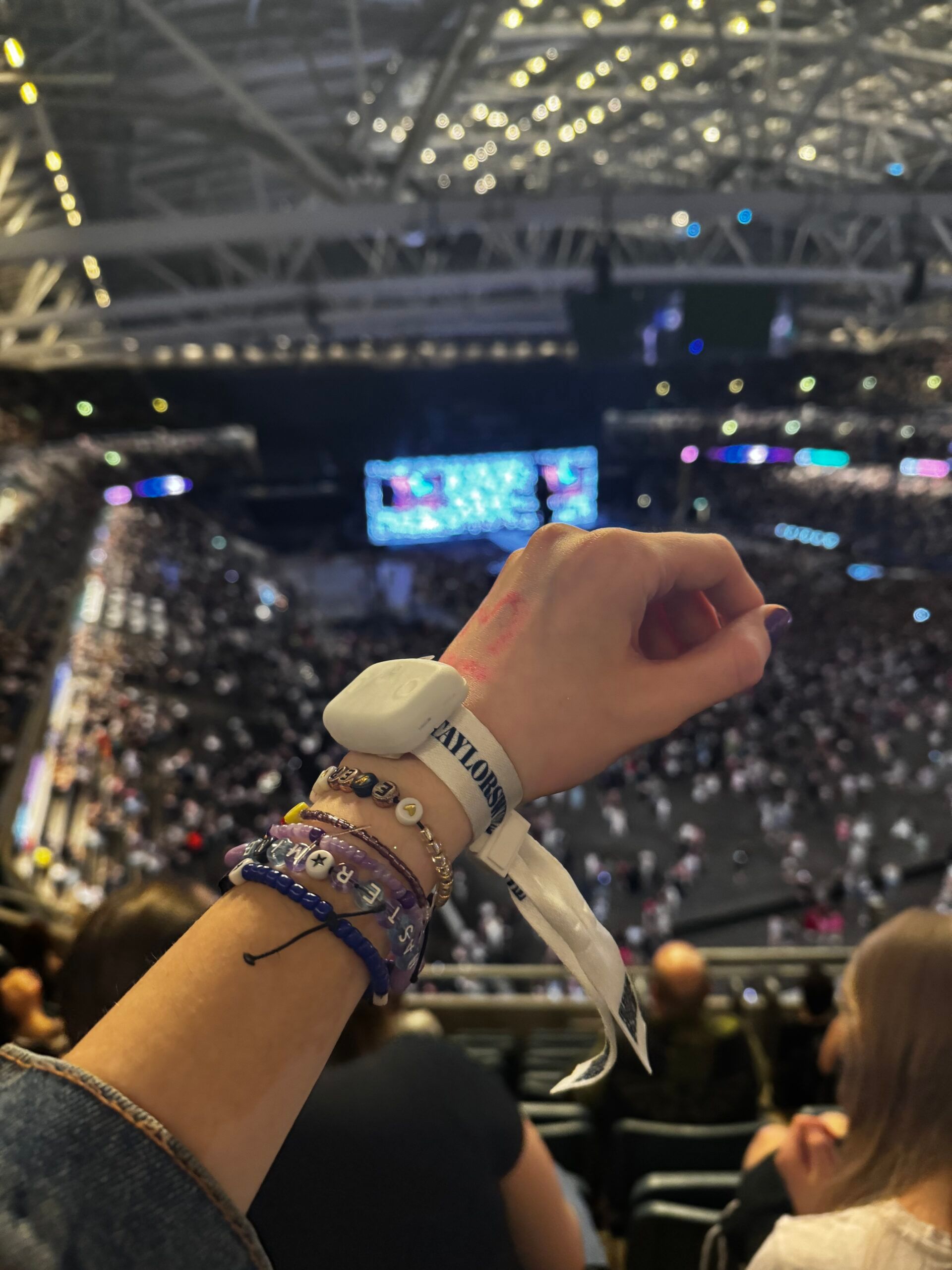 A girl focusing on her light-up wristband at a Taylor Swift concert